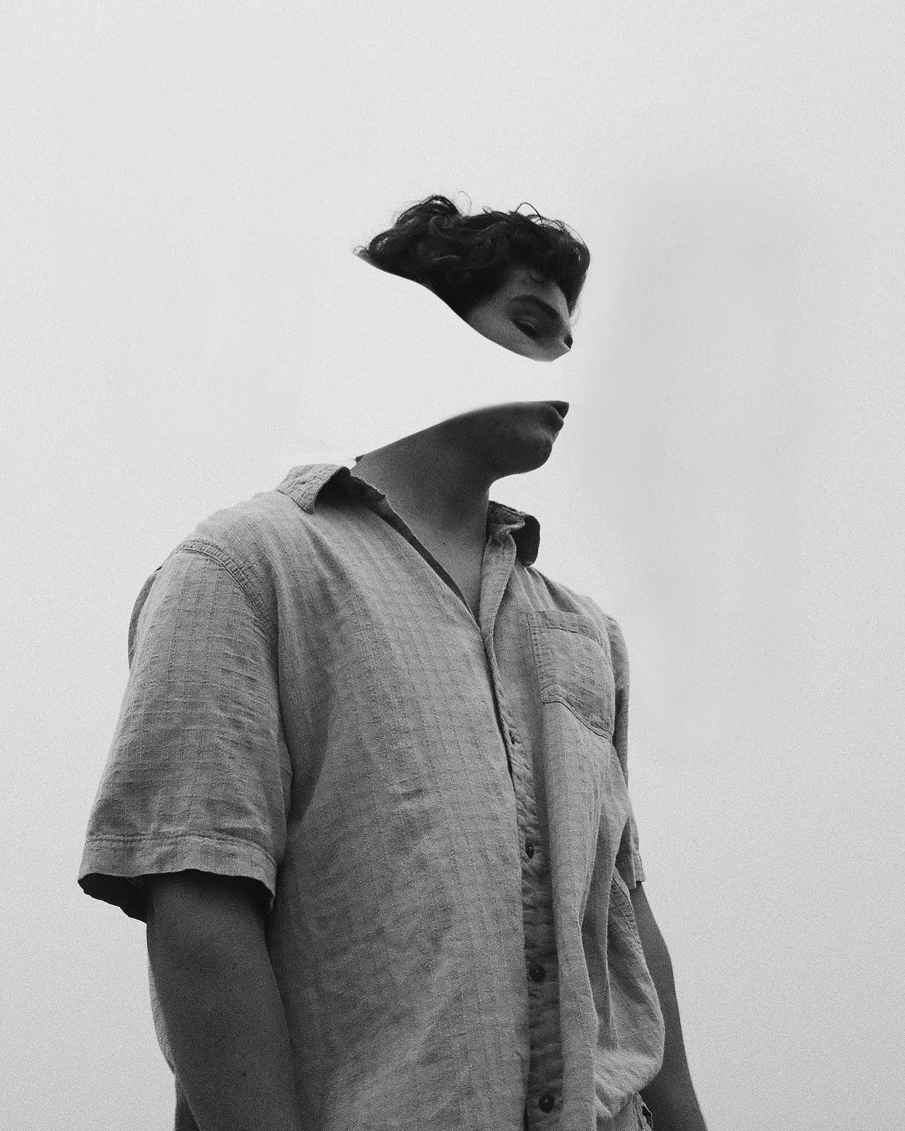 Black and white surreal portrait of a person in a linen shirt with face obscured by floating hair.