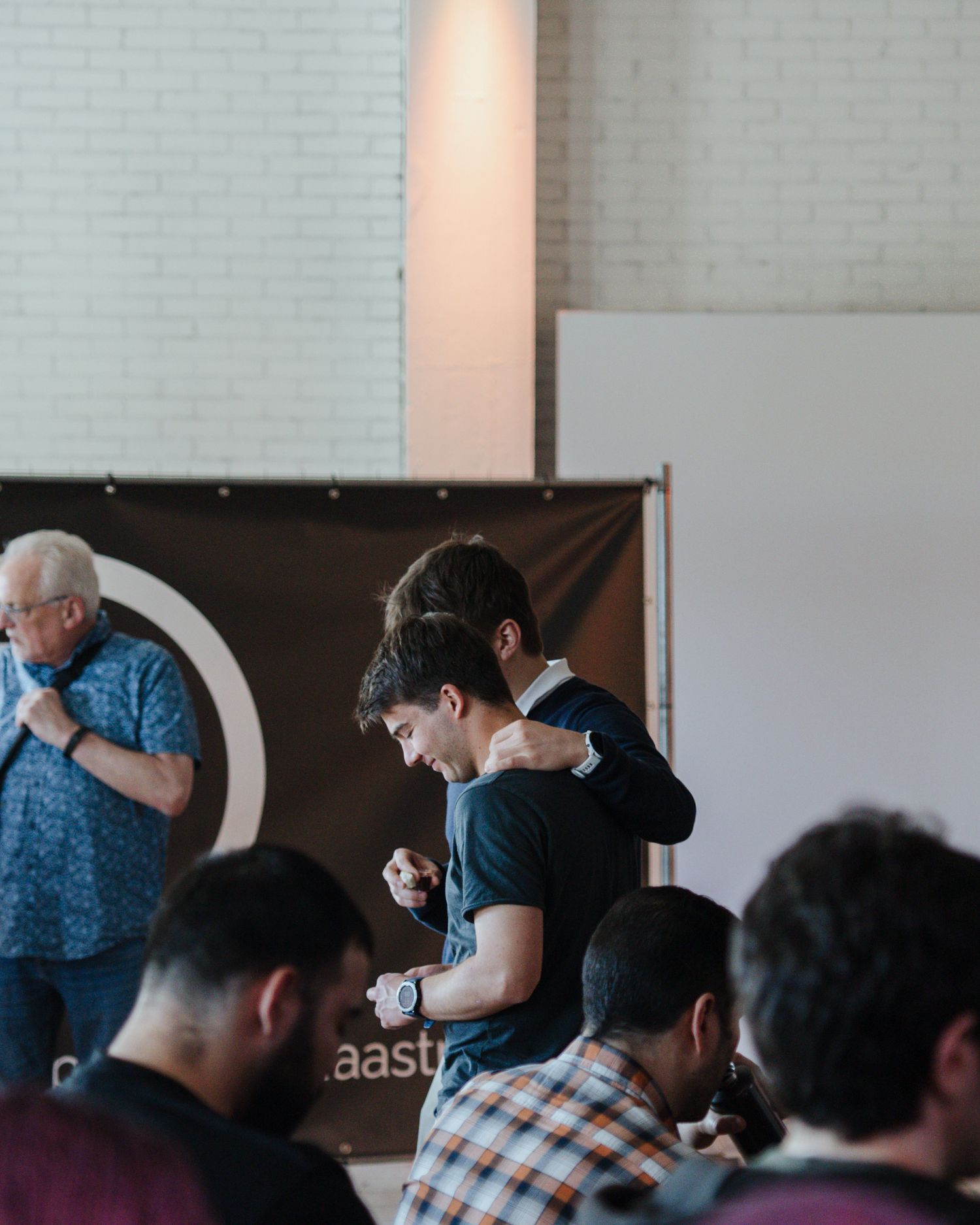 Young man praying with bowed head beside an older speaker at a Christian conference event.