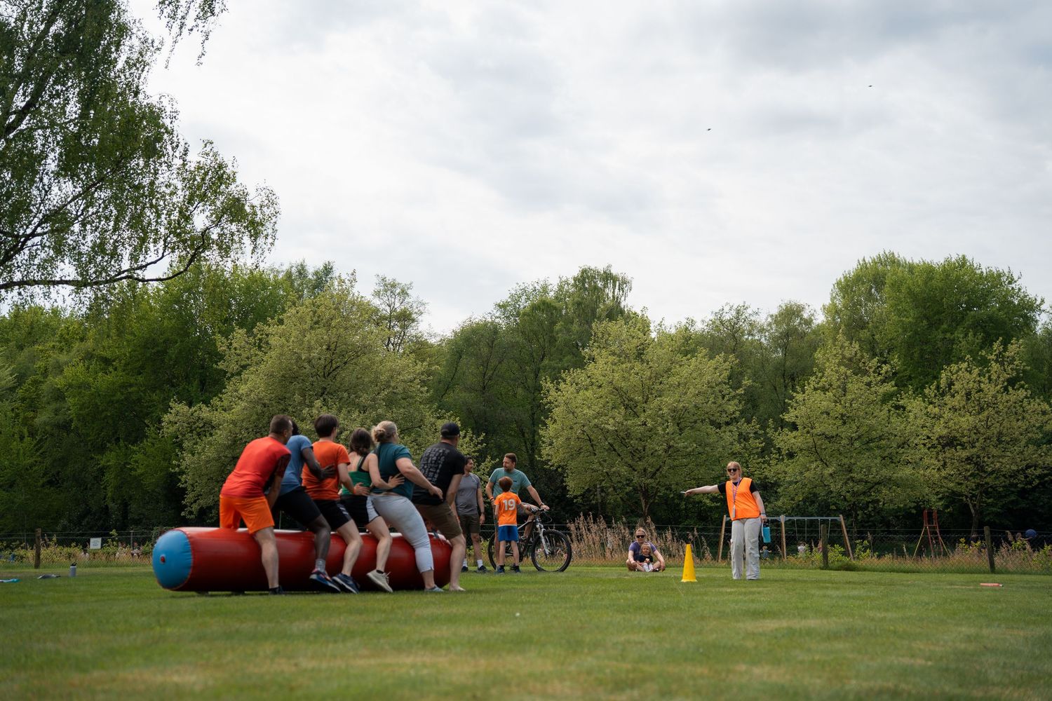 Team of participants in orange shirts compete in an outdoor group activity on a grassy field.