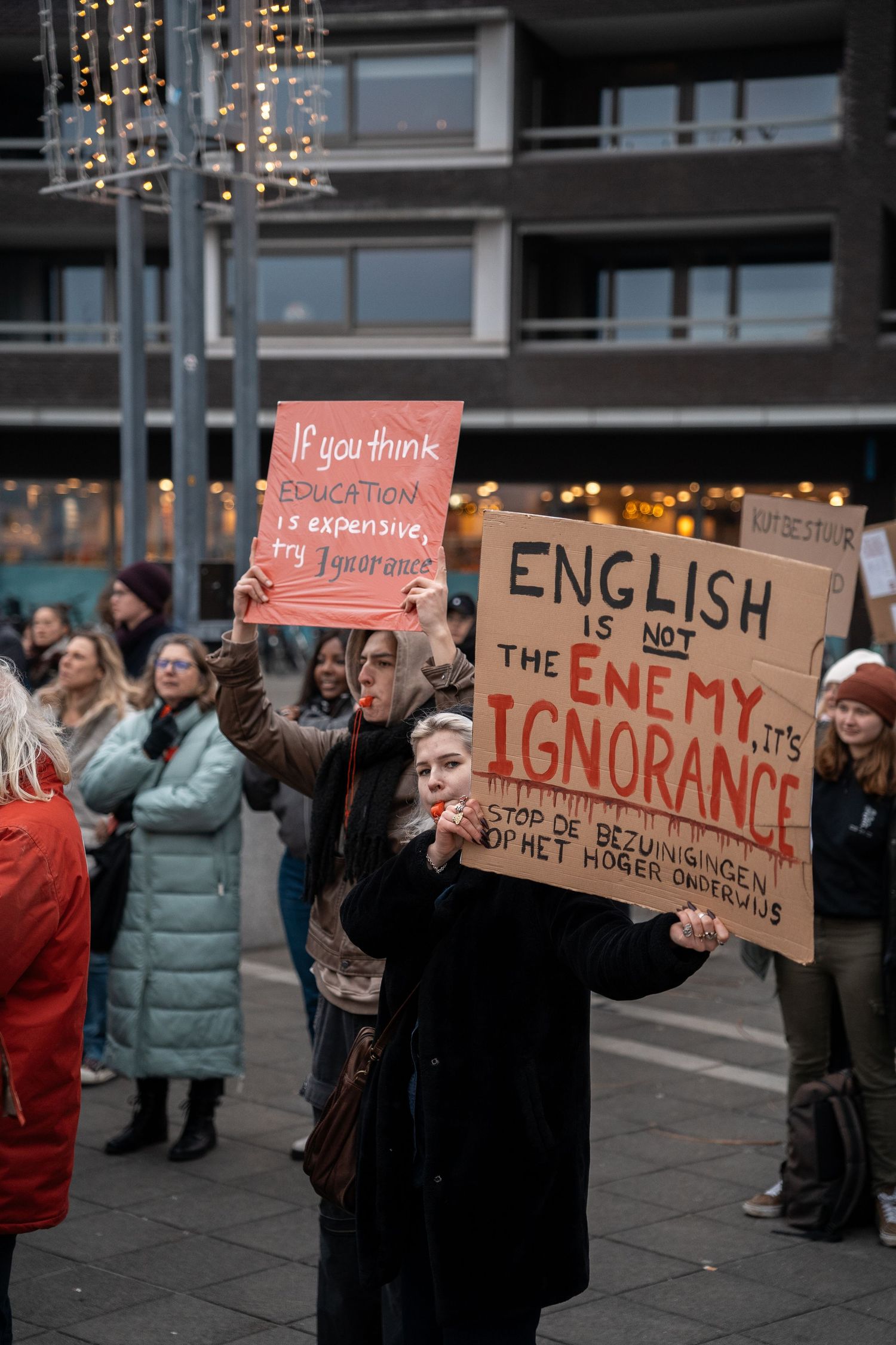 Protesters holding signs reading English is Not the Enemy its Ignorance at a Dutch education rally.