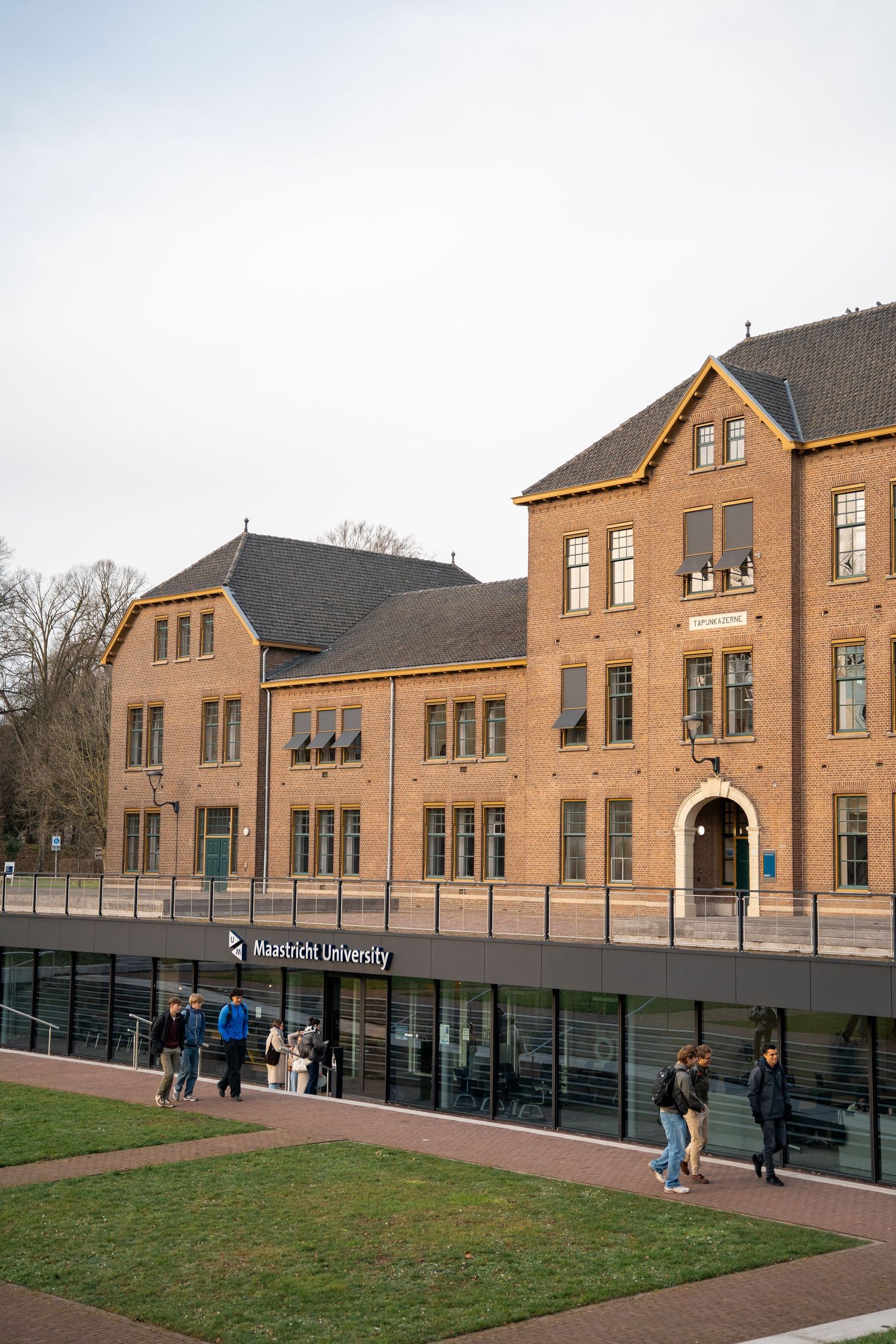 Historic brick Maastricht University building exterior with students walking outside.