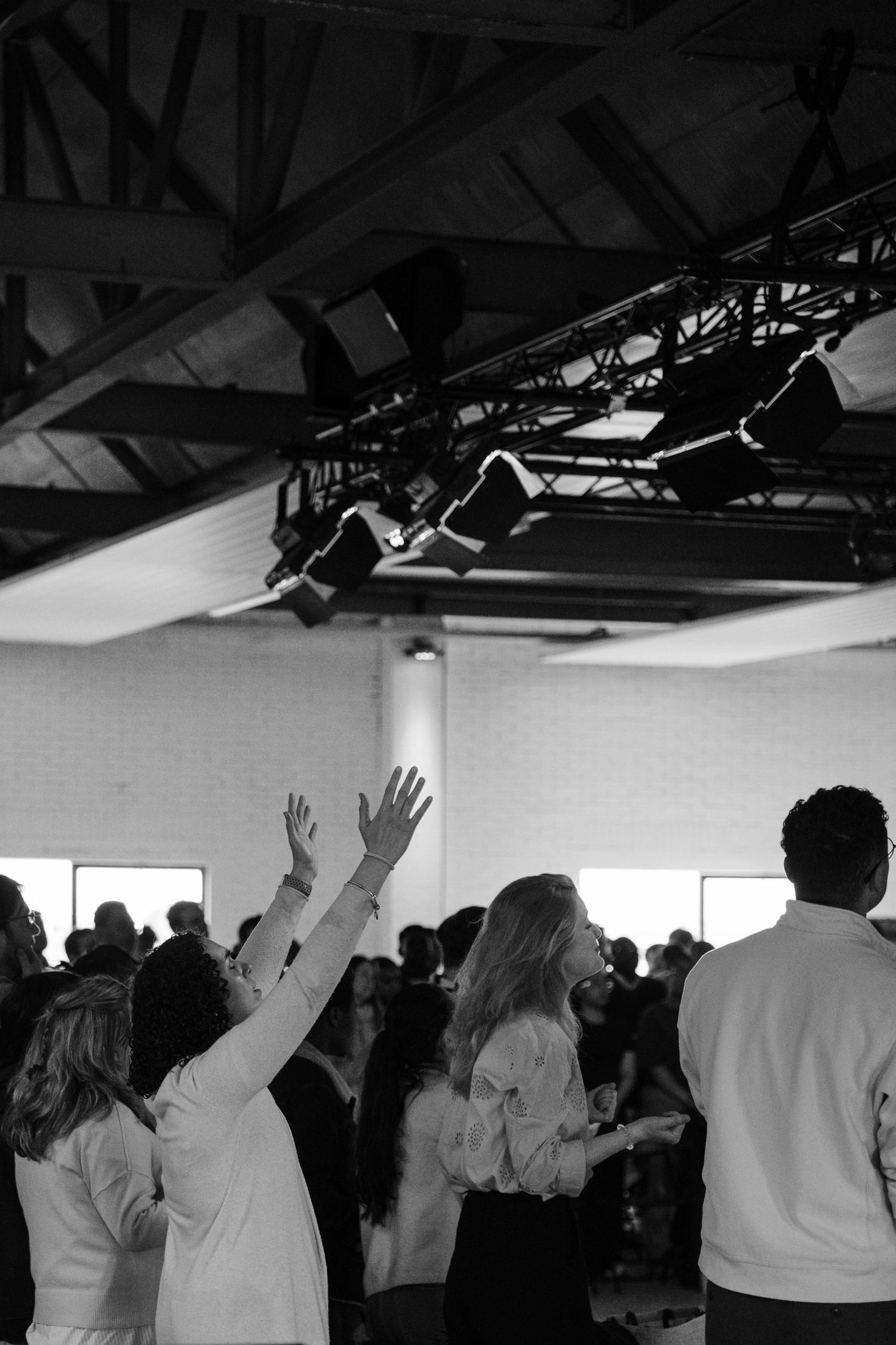 Black and white photo of congregation members raising hands in worship during a church praise service.