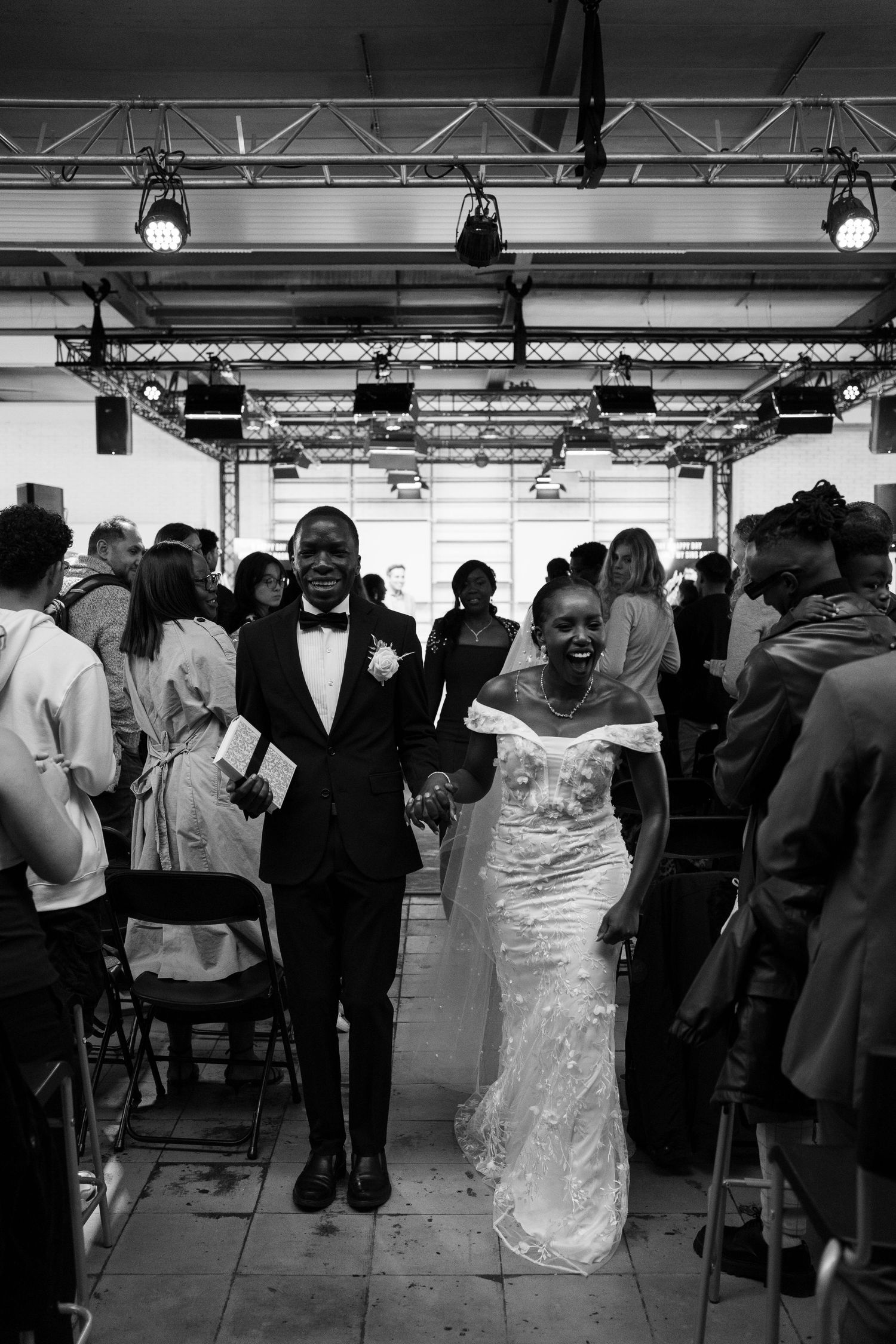 Black and white photo of joyful newlyweds walking hand in hand down the aisle after their ceremony.
