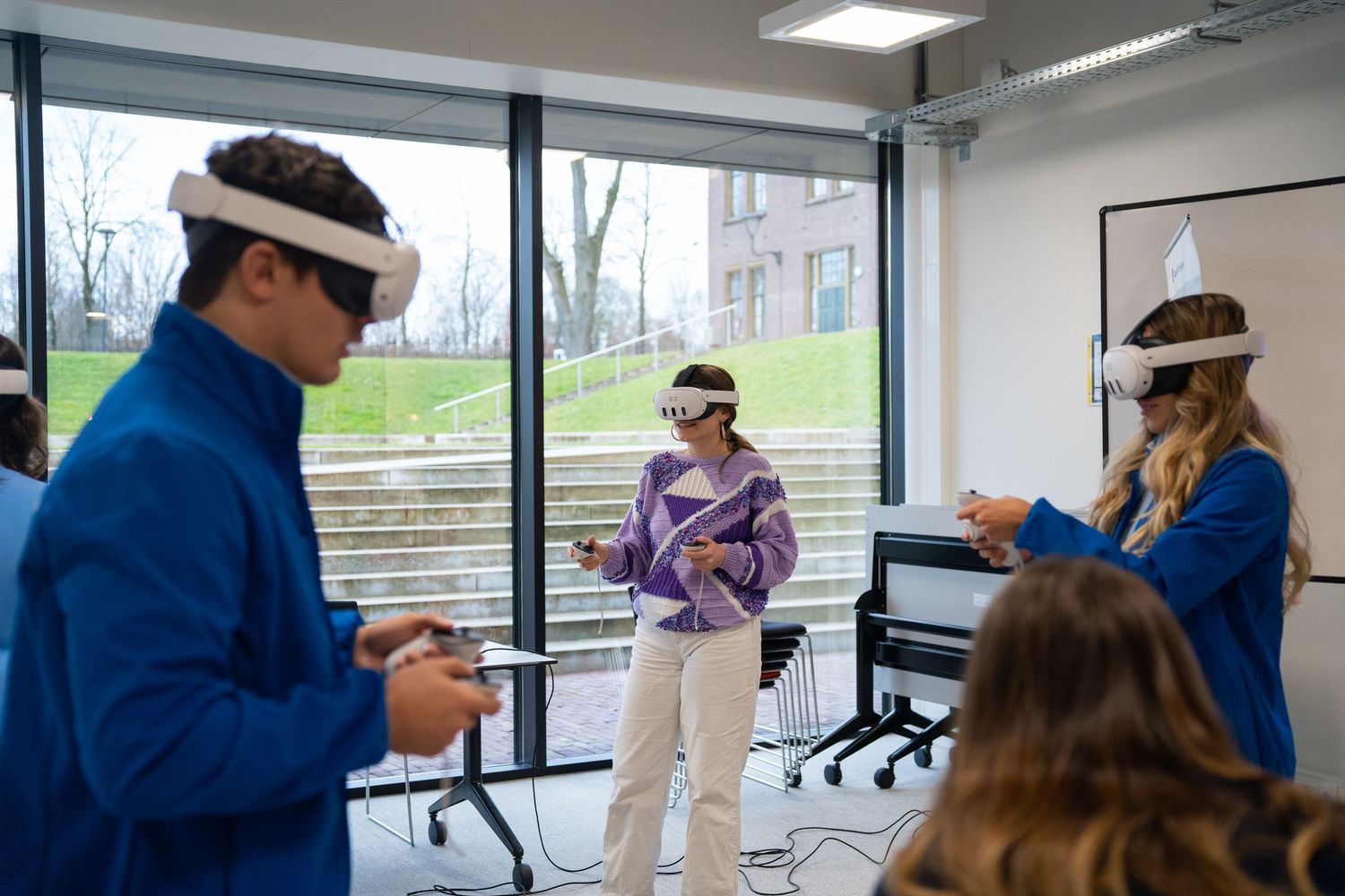 Three students use VR headsets during an interactive technology session in a modern university classroom.
