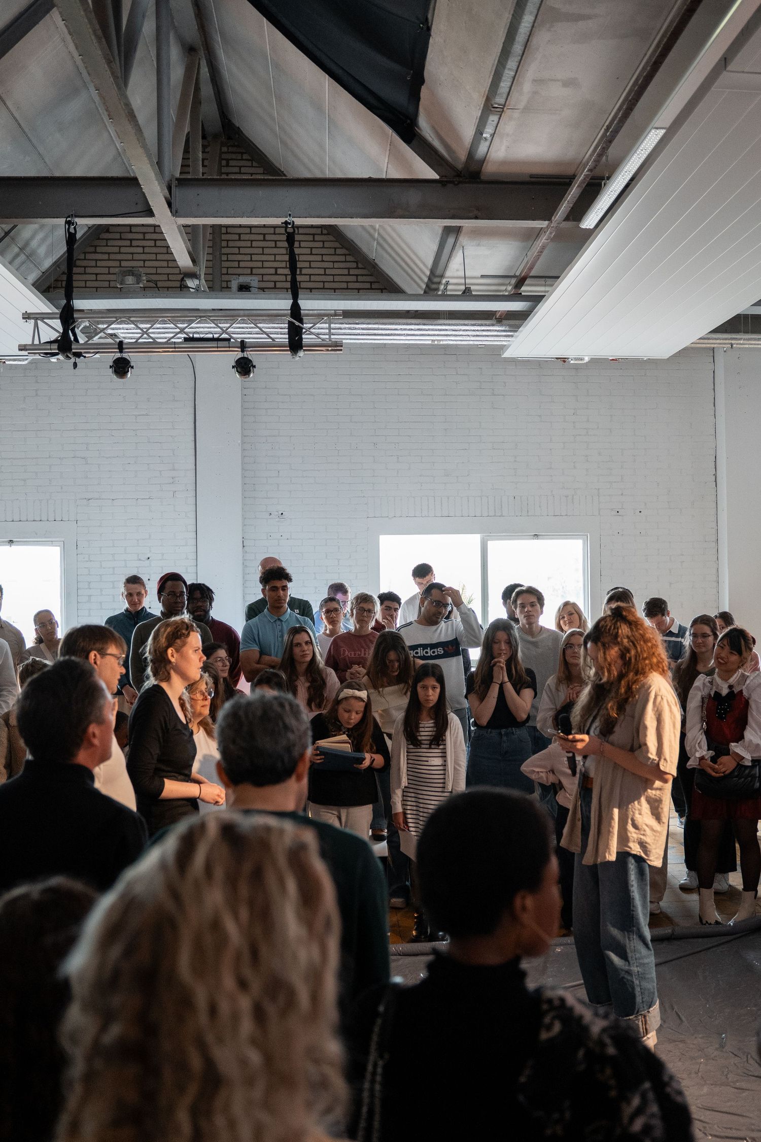 Large group of students gathered in bright white industrial event space.