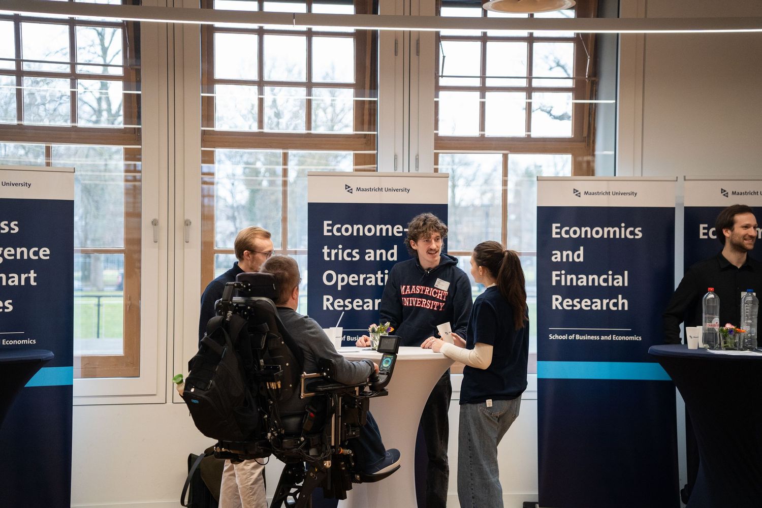 Students explore econometrics and economics program booths at a university open day information fair.