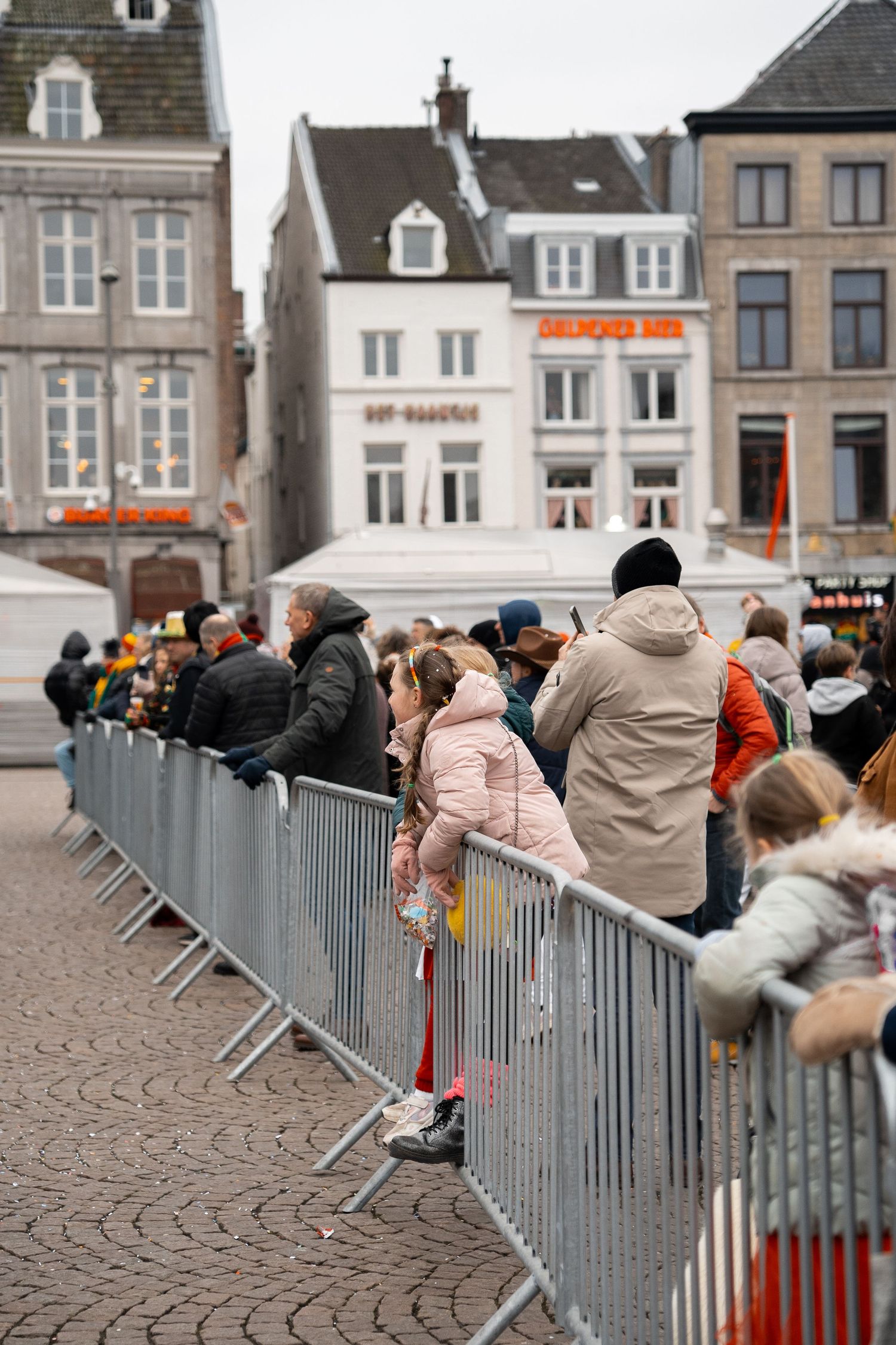 Crowd of people standing behind metal barriers at a public event in Maastricht.