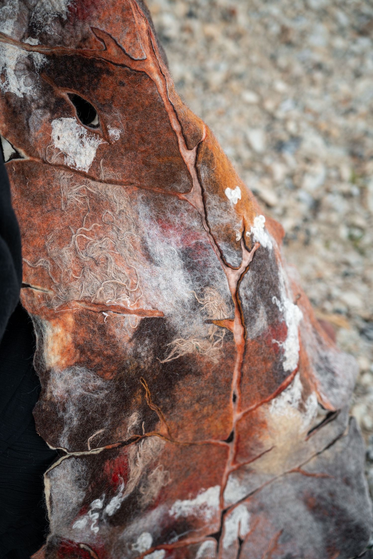 Close-up detail of a textured felted artwork in rust and brown tones with organic patterns.