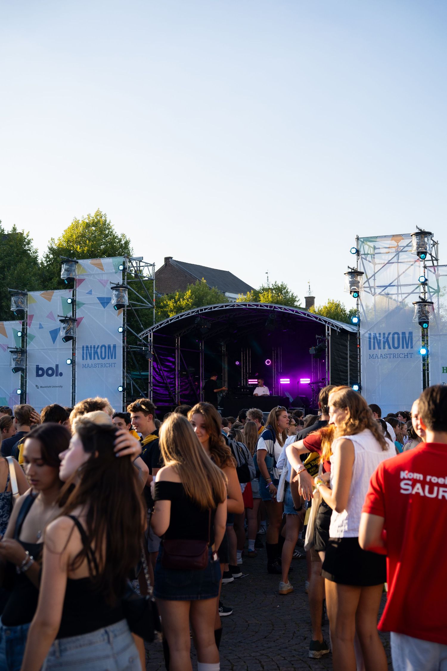 Large crowd of students gathered at outdoor INKOM festival stage at dusk.