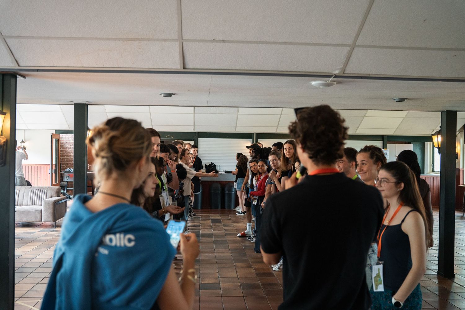 Group of young people gather in an outdoor corridor during a break at a Christian youth conference.