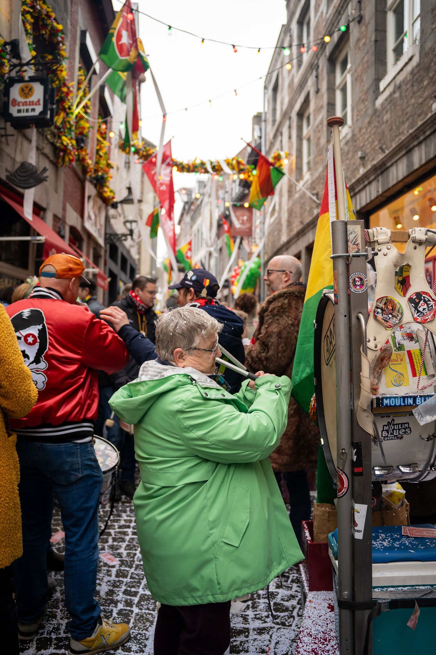 People browsing a busy carnival street market decorated with colorful flags and streamers.