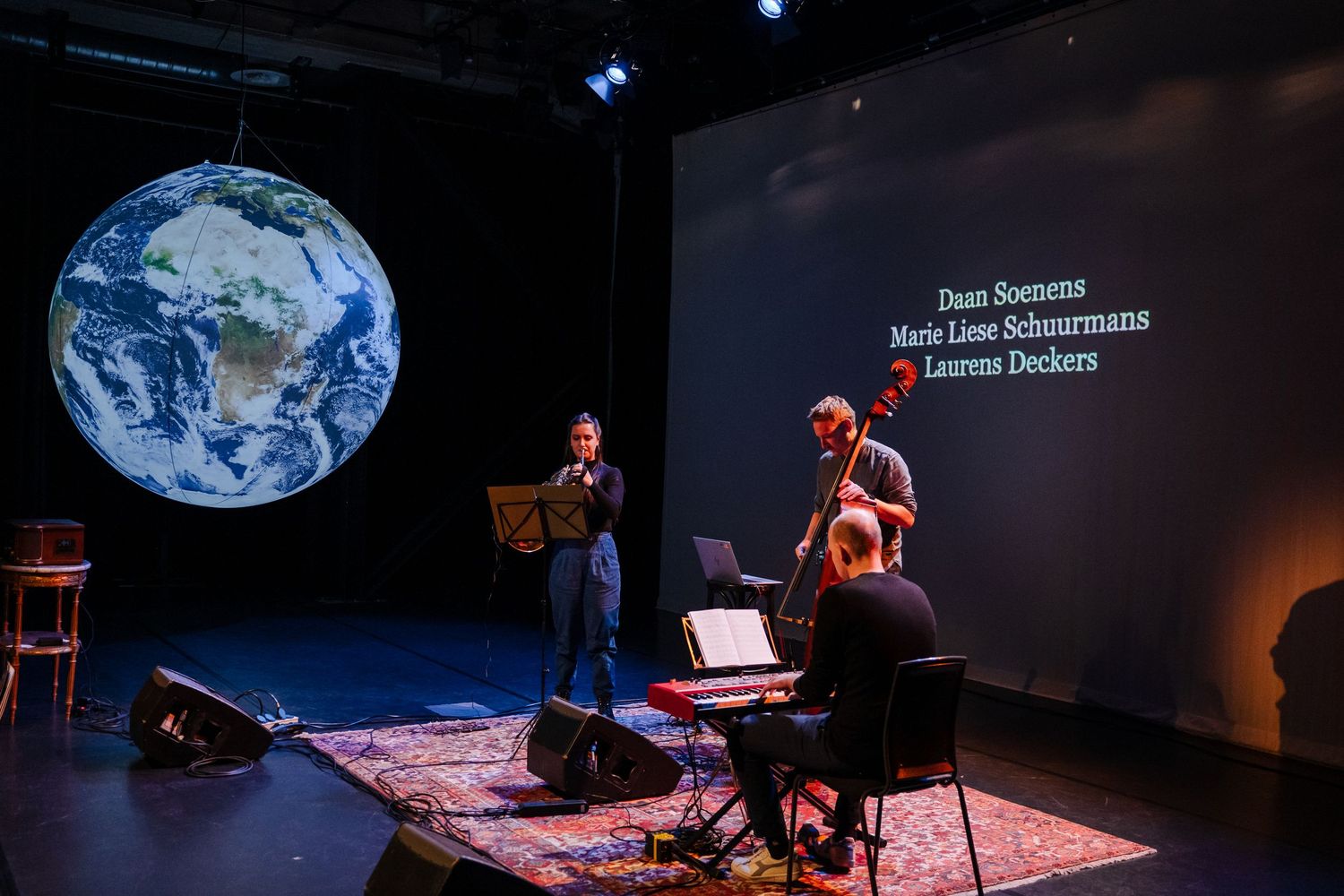Musicians performing on stage with Earth projection at Maastricht University event.