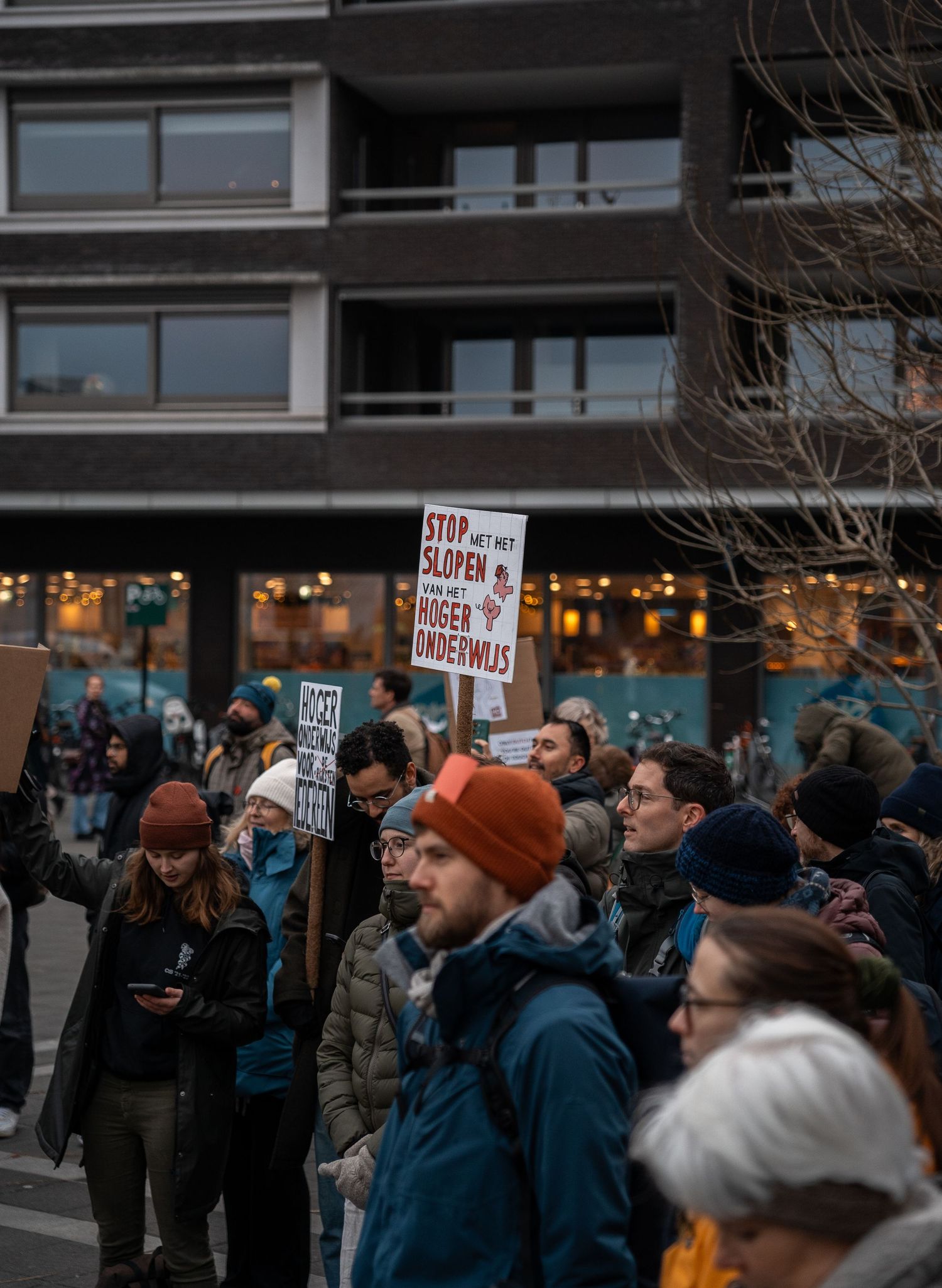 Protesters march holding a Dutch sign reading Stop met slopen van het onderwijs at a demonstration.