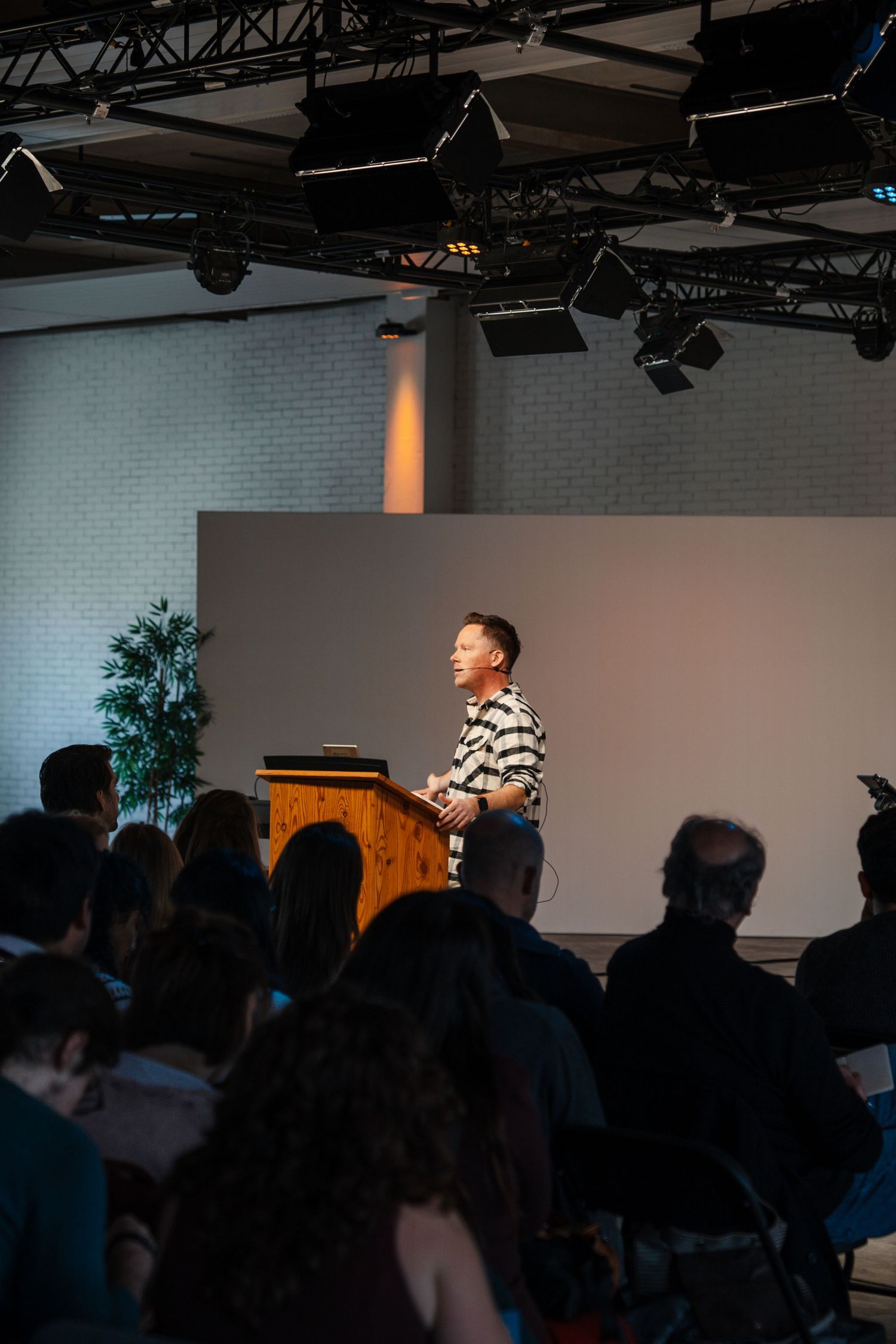 Speaker at a wooden podium addressing a seated congregation in a contemporary church auditorium.