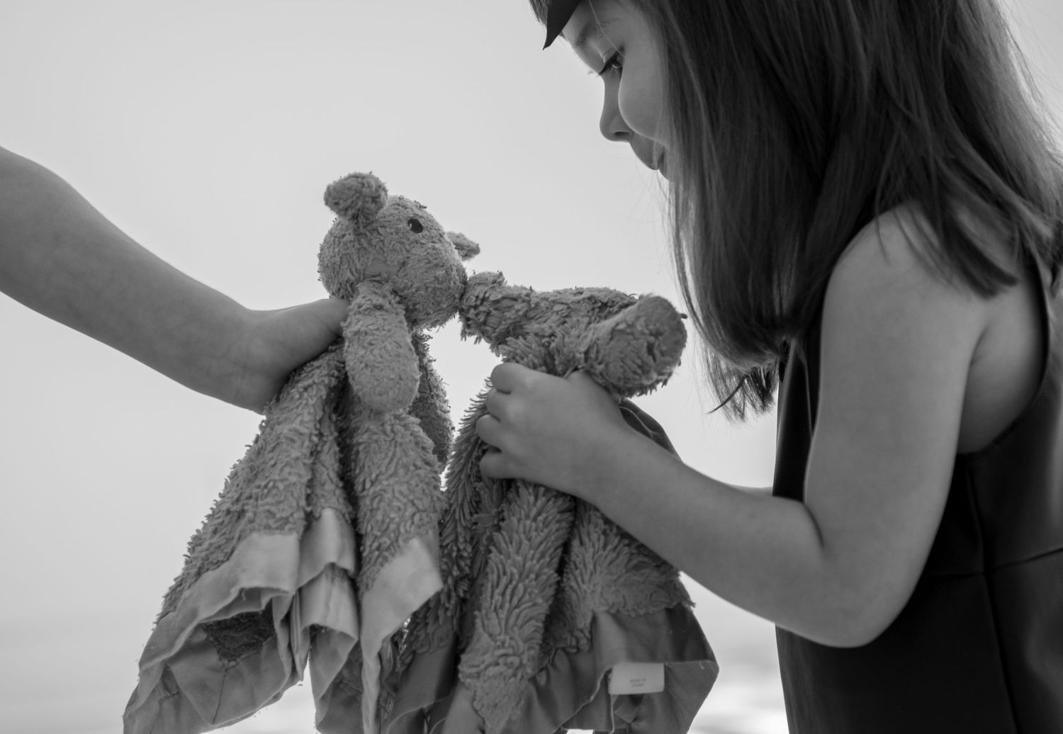 Black and white close-up of young girl holding a stuffed animal teddy bear toy.