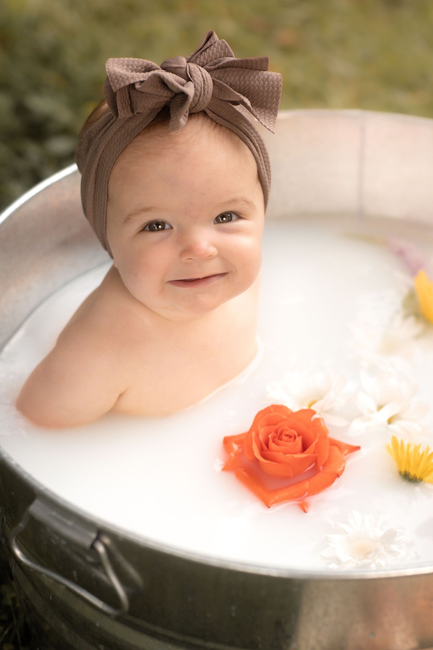 Milk bath outdoor photography session.  Waukesha Wisconsin.  Baby is smiling and comfortable with the natural oils and calming surroundings
