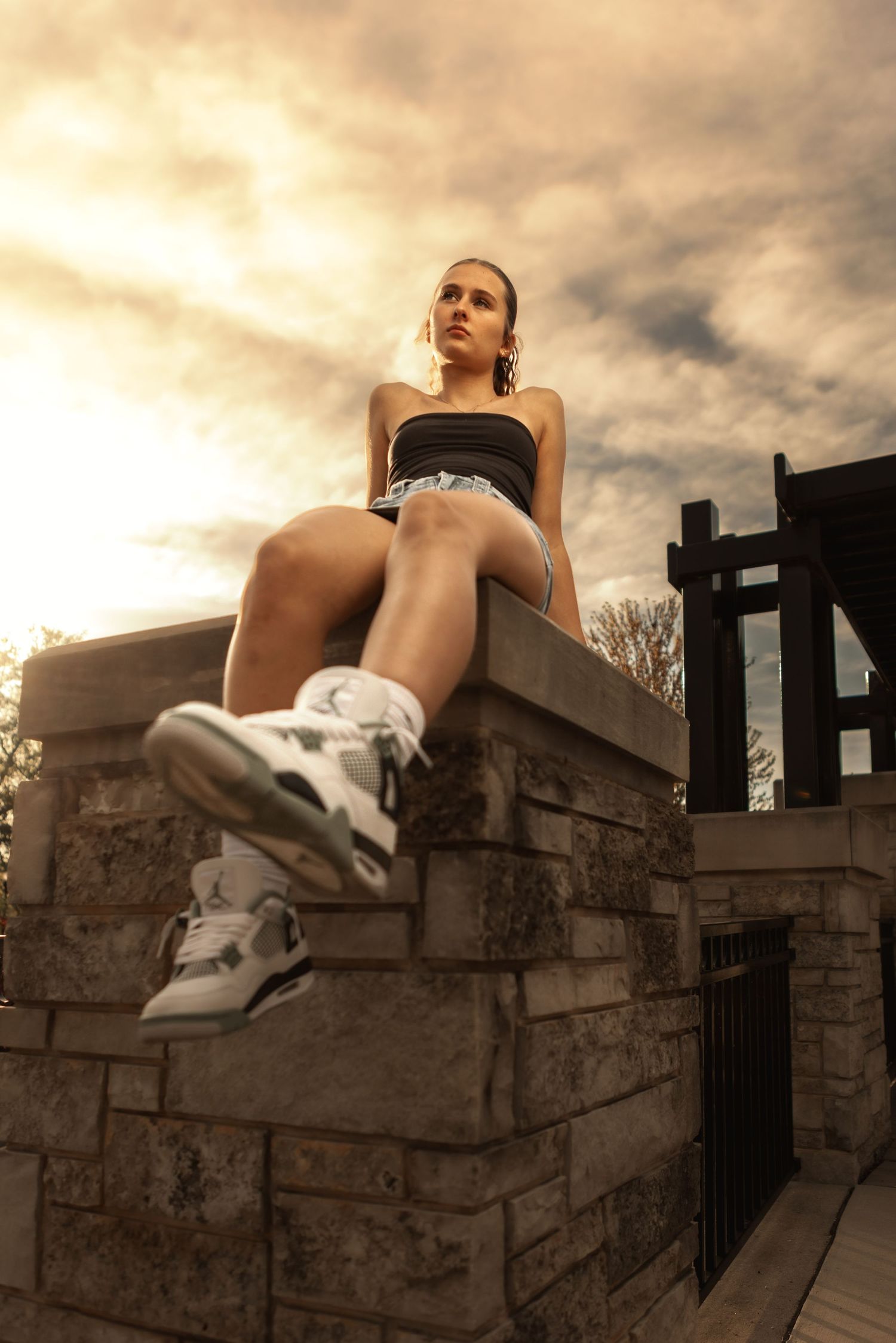 Girl sitting in downtown Waukesha with dramatic clouds. Elegant, cinematic portrait capturing mood, style, and individuality.