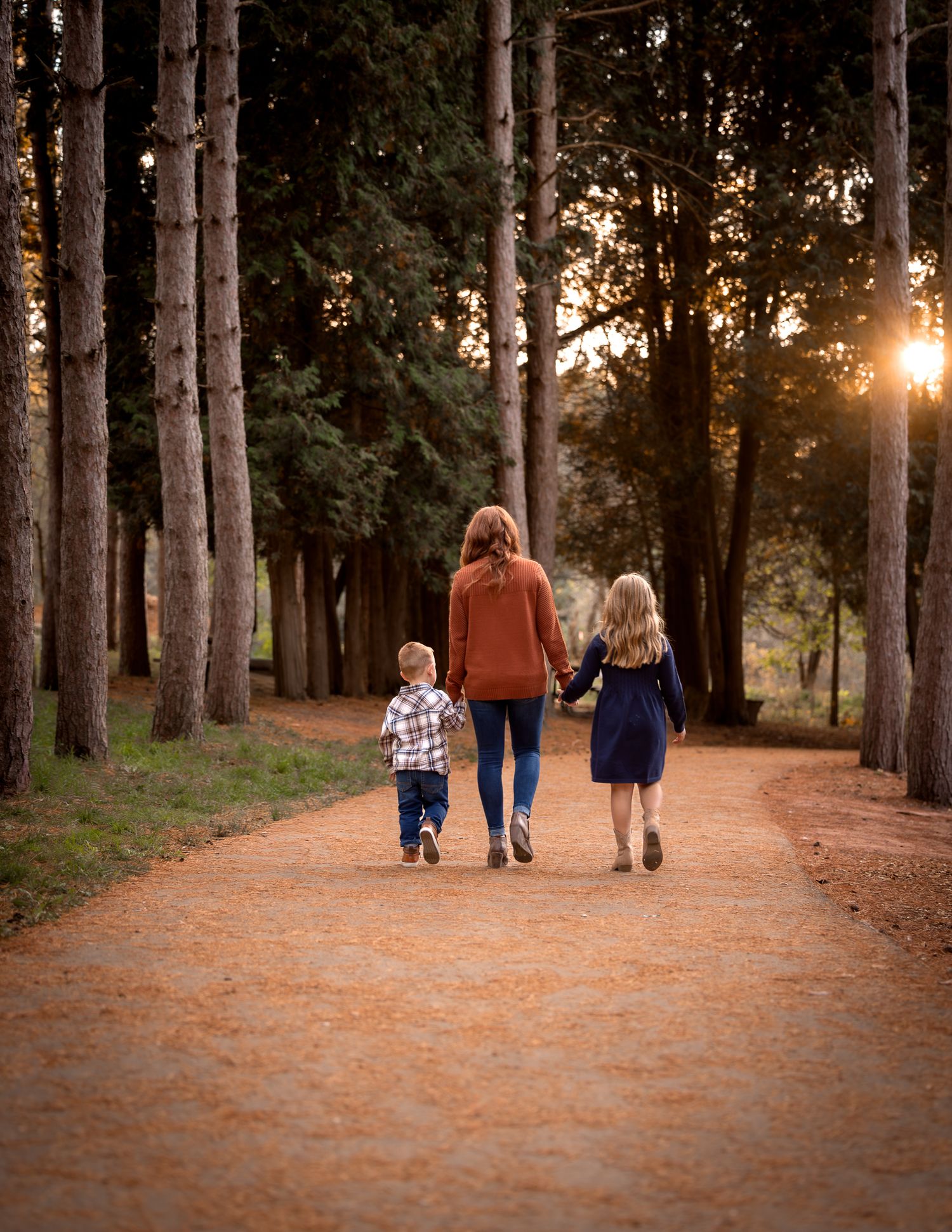 Fall family session at Retzer Nature Center, Waukesha. Mother and two kids walking down a pine-lined path in warm, vibrant portraits.