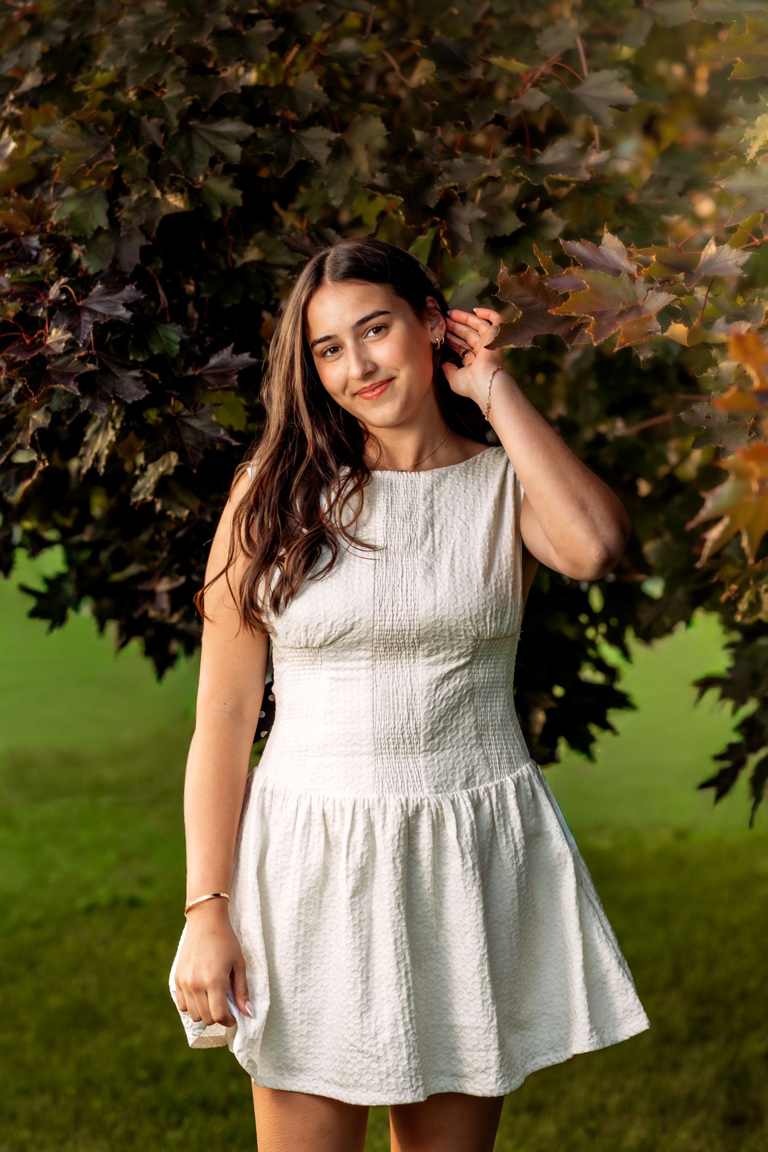 Hartland senior photography. Teen sitting outdoors in a field near trees, creating relaxed, elegant, and heartfelt portraits.