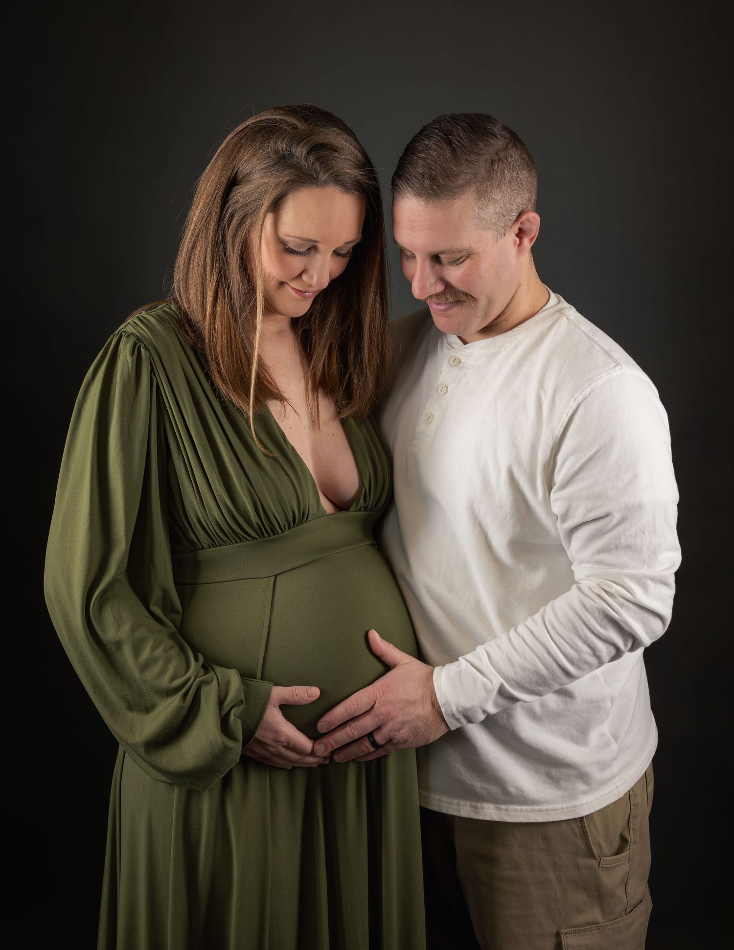 Husband and wife maternity session at Lake Country Photography, Waukesha. Mom in green dress, intimate, warm, and luxury studio portraits.