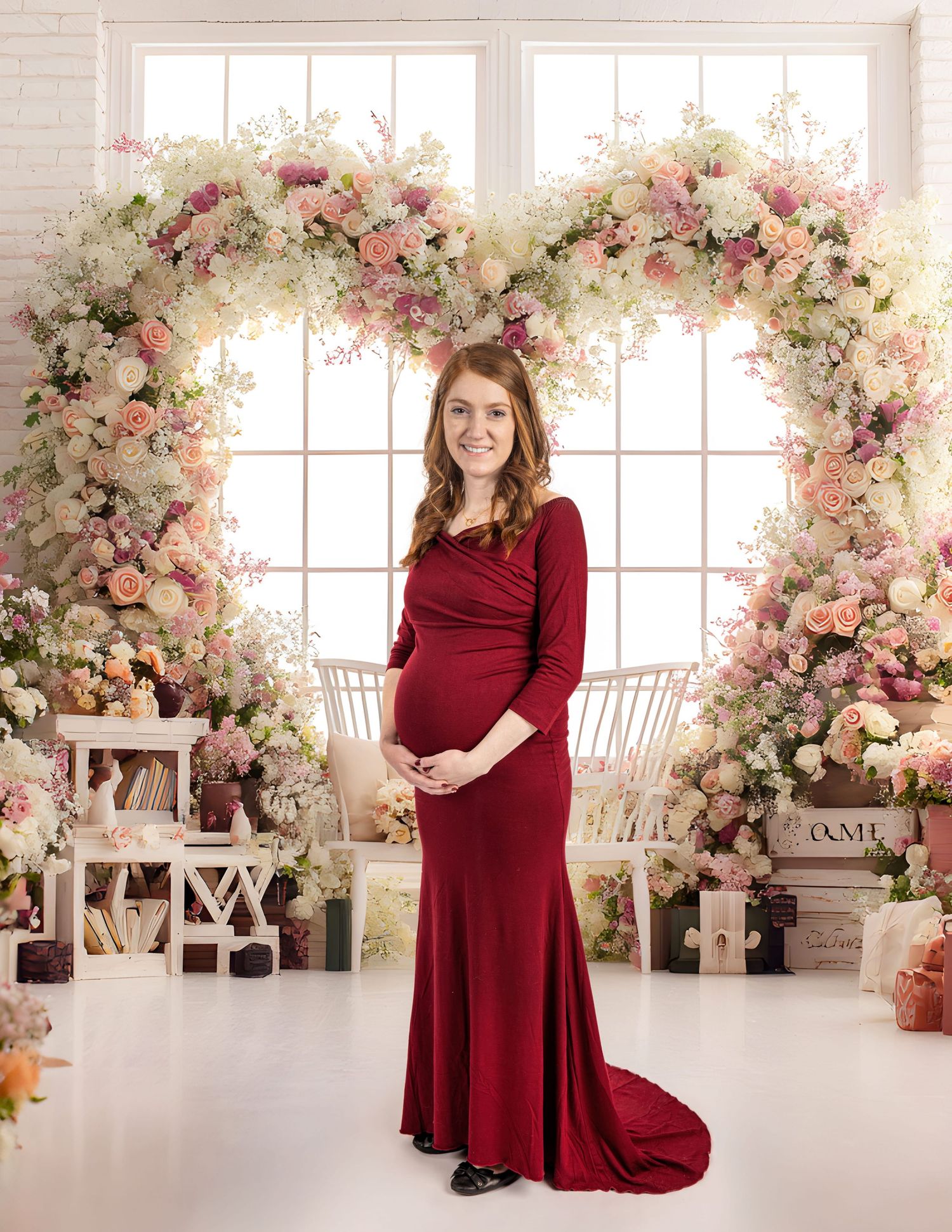 Maternity Studio Session.  Excited Mother stands confidently holding belly, Natural light pours through big window.  Flowers  surround