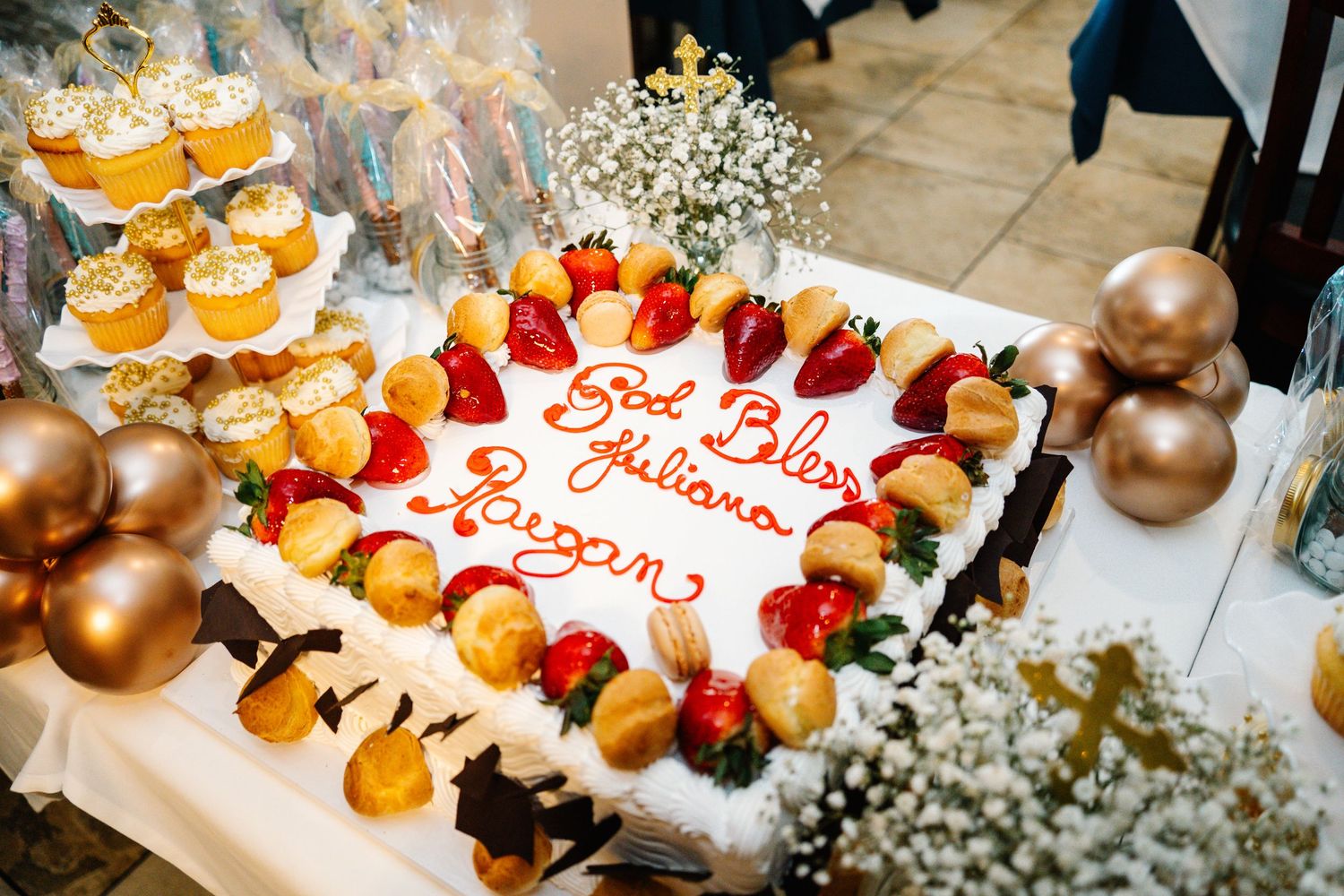 A beautifully decorated cake with strawberries and baby's breath flowers surrounded by cupcakes.