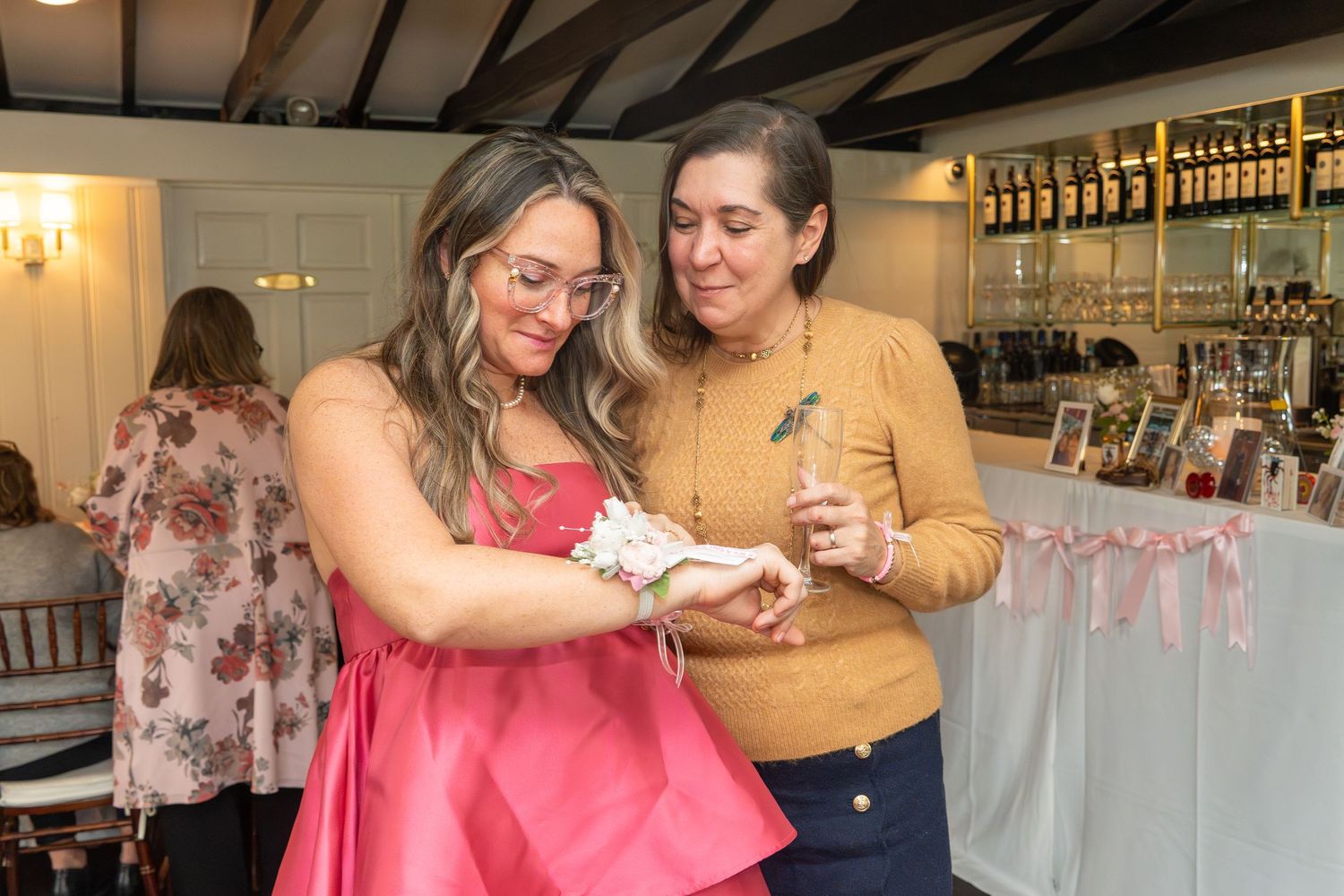 Two attendees examine a small gift together at a baby shower celebration.