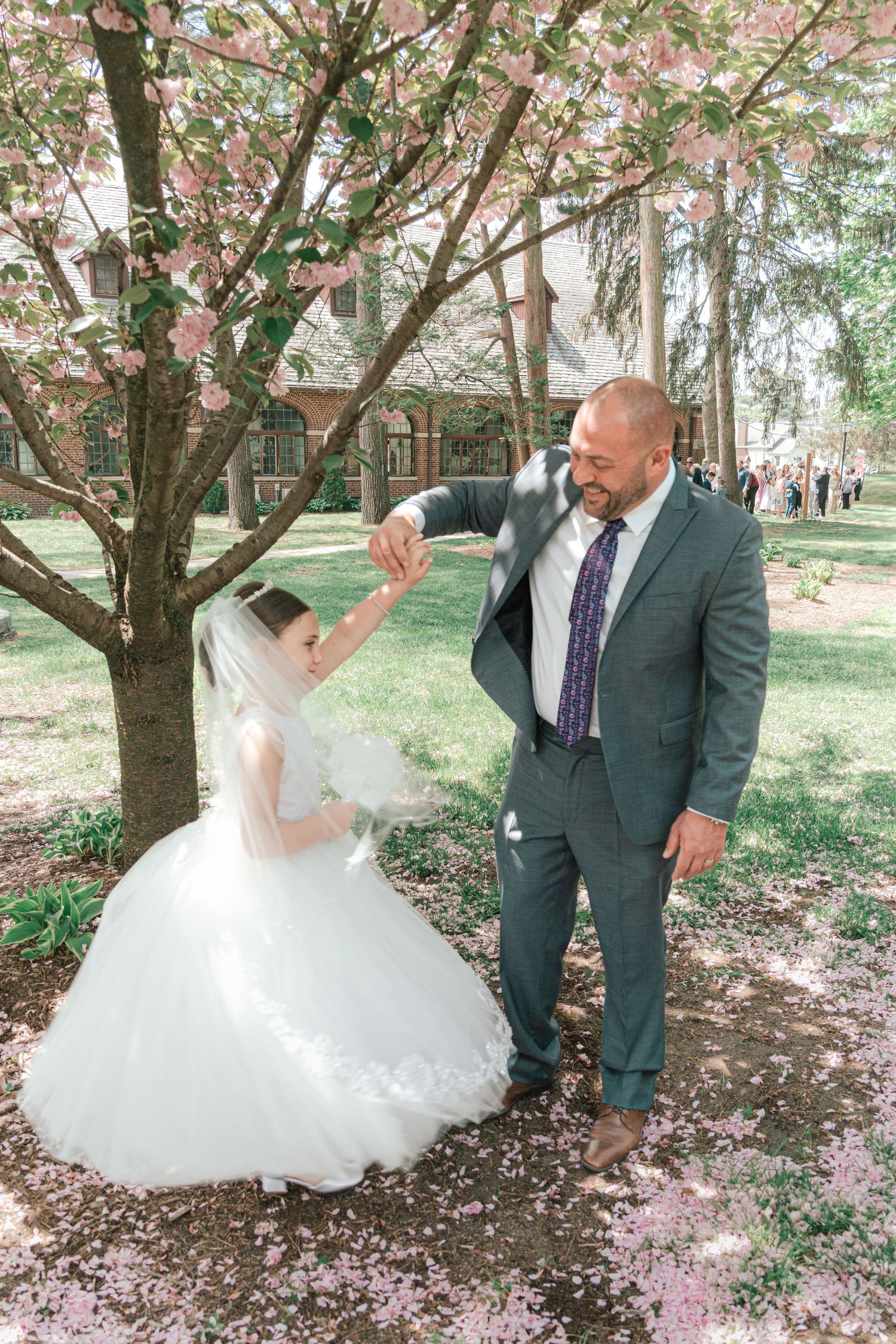 A couple dances under blooming cherry blossom trees in a romantic garden setting.