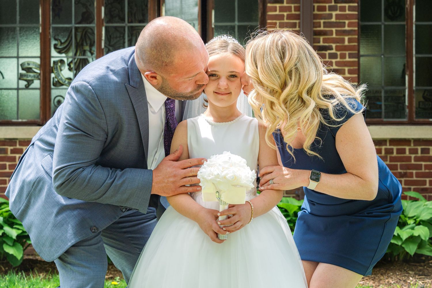 A couple shares intimate moments in a garden setting wearing formal attire.