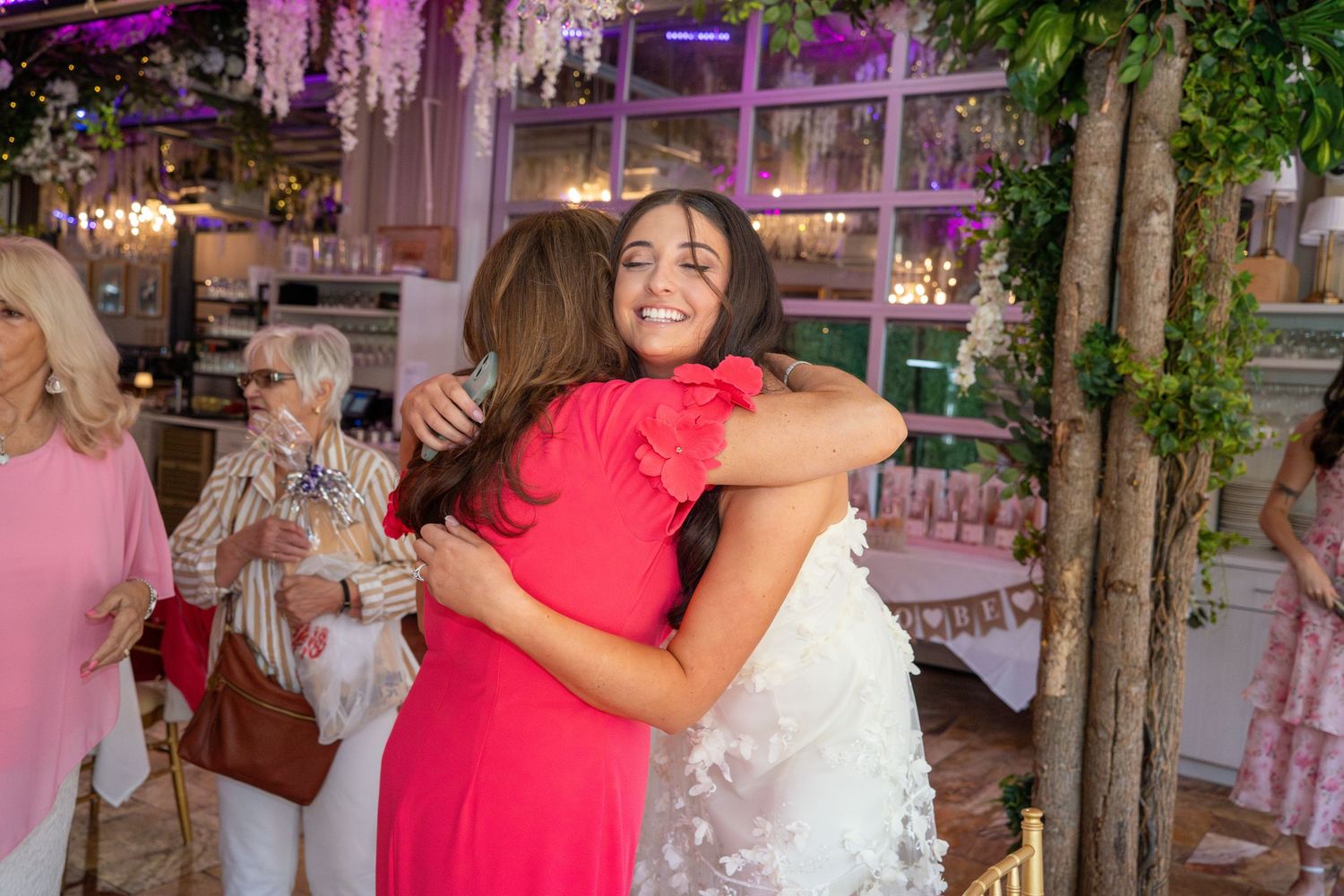 Floral decorations and pink lighting create an elegant bridal shower atmosphere.