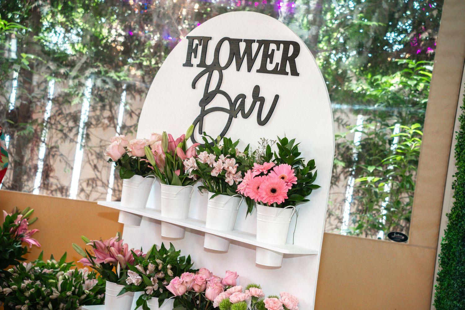 A decorative flower bar display with pink blooms and white containers at an event.