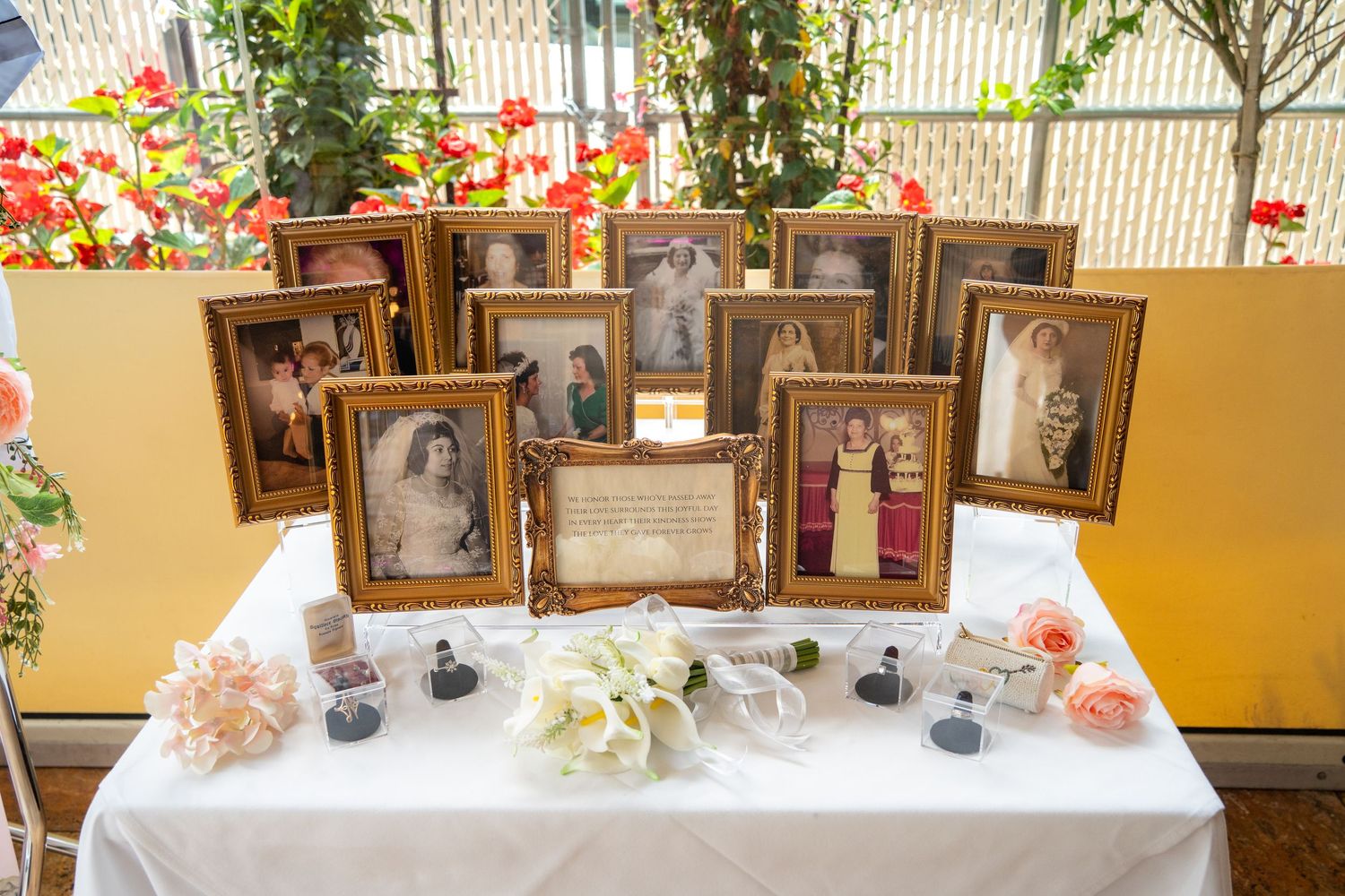 A memorial table display with vintage framed photos and white flowers on a decorated surface.