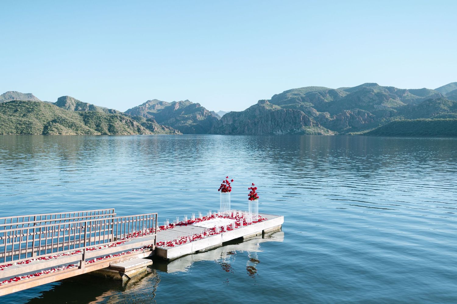 A series of connected floating docks extend into a serene mountain lake surrounded by rugged peaks.