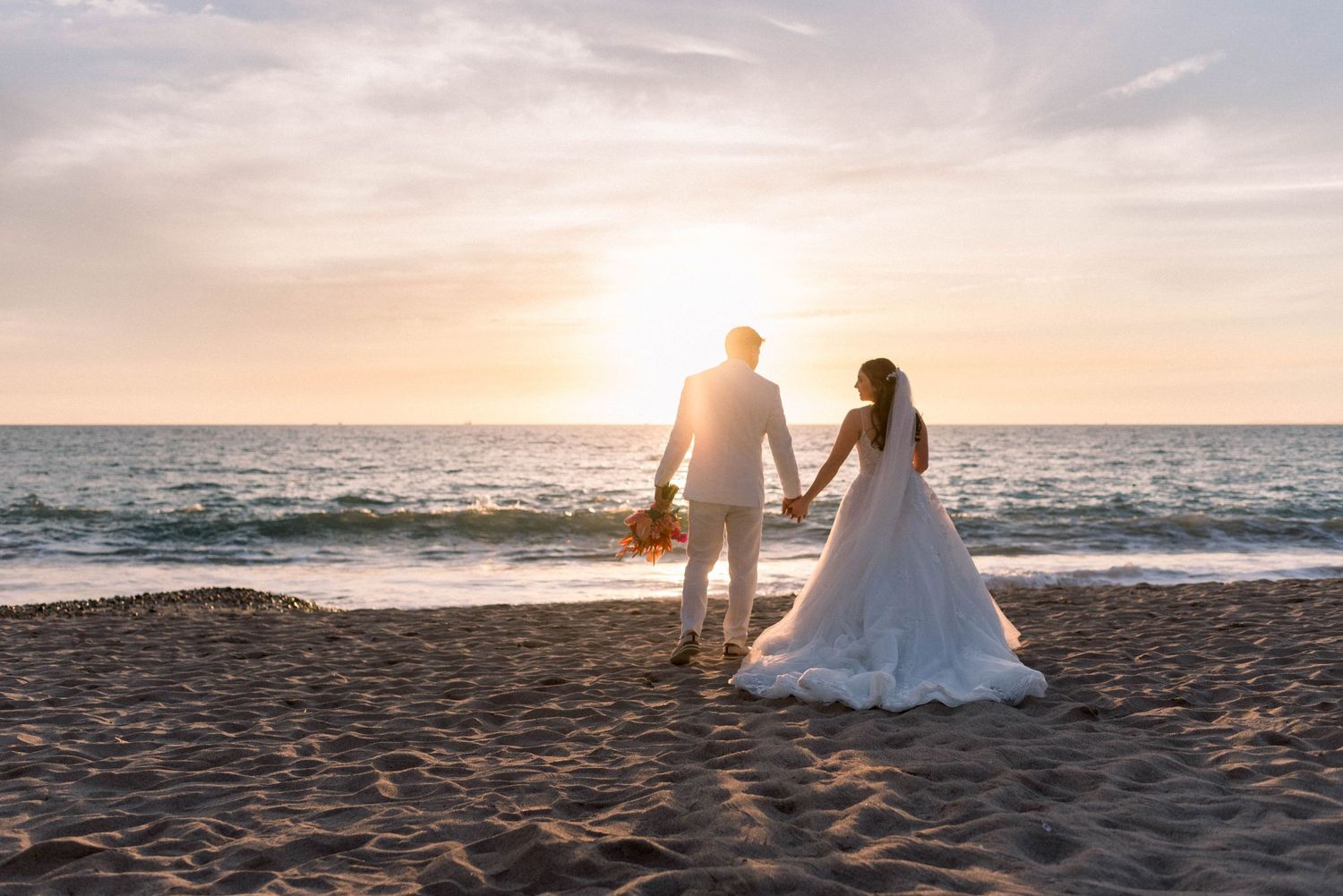 Romantic beach sunset scene with silhouettes walking along the shoreline.
