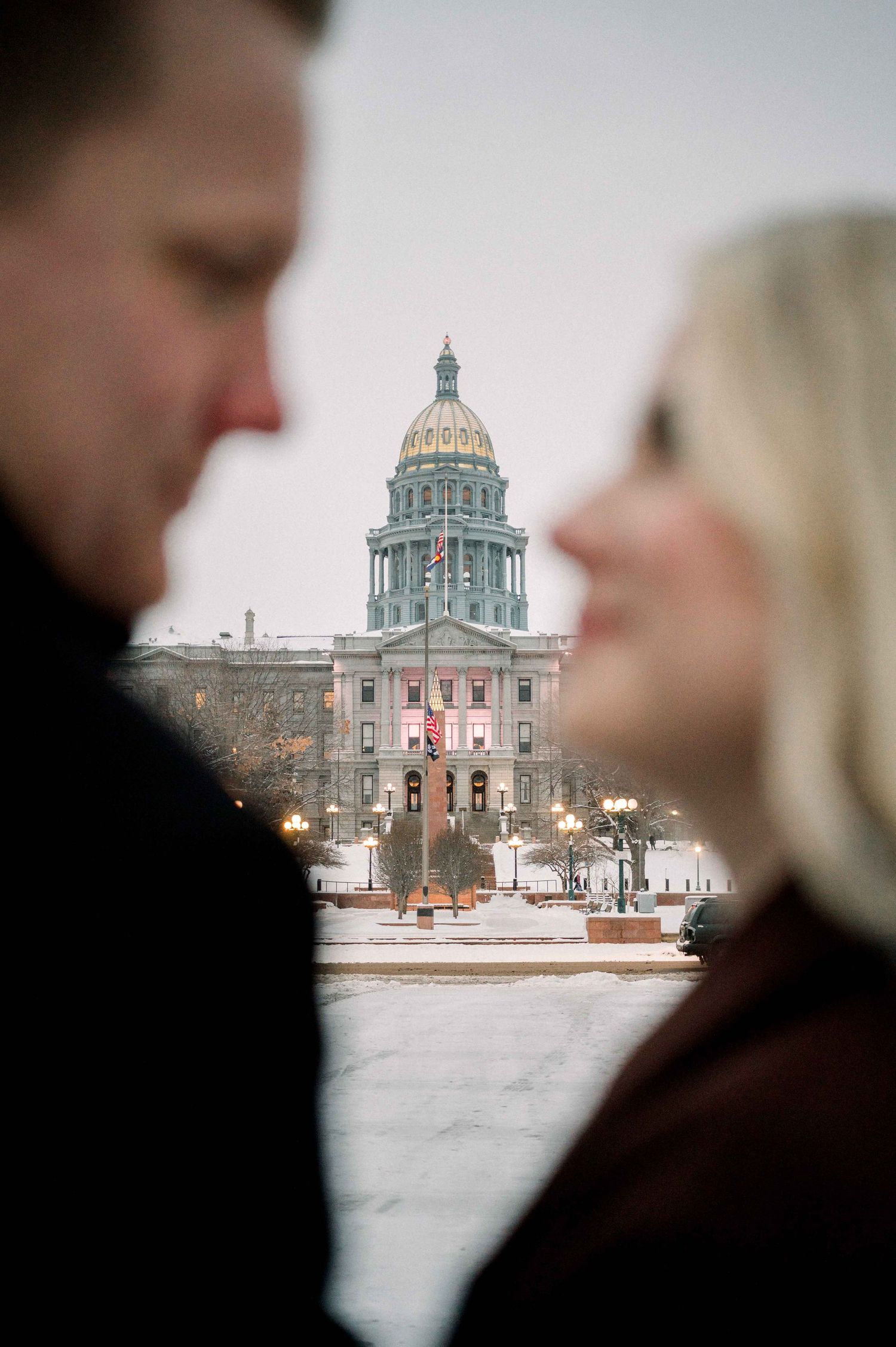 Intimate portrait of couple with historic capitol building dome in winter background.