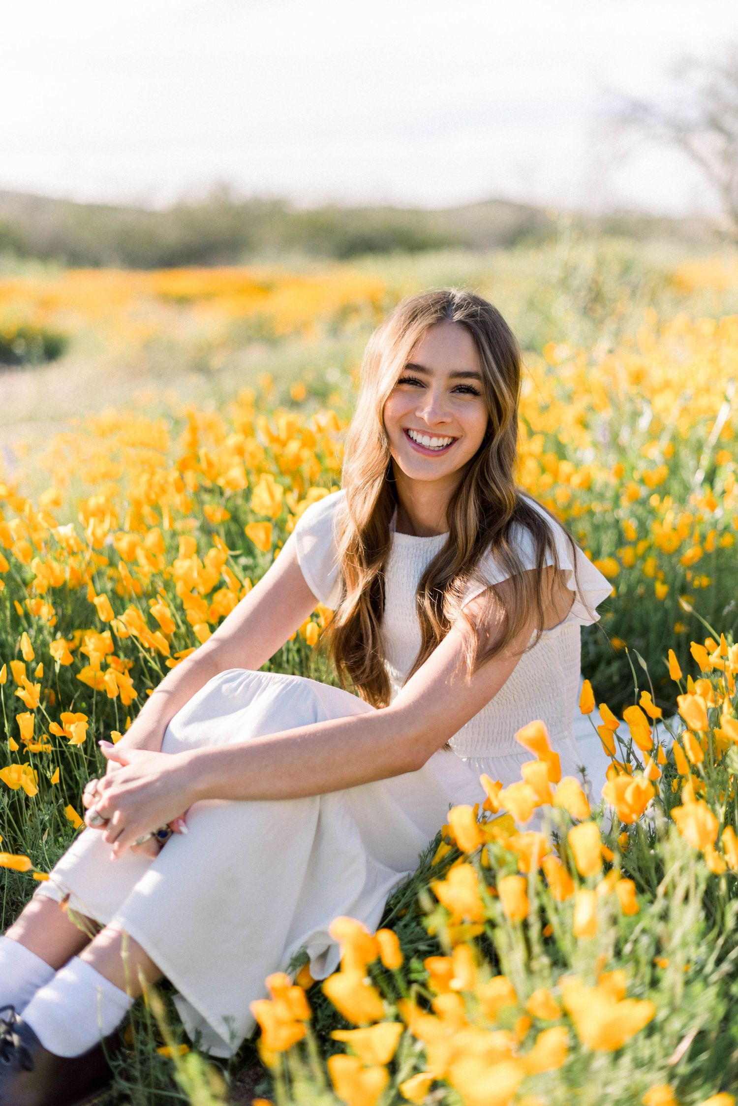 White dress contrasts beautifully with vibrant field of yellow wildflowers on sunny day.