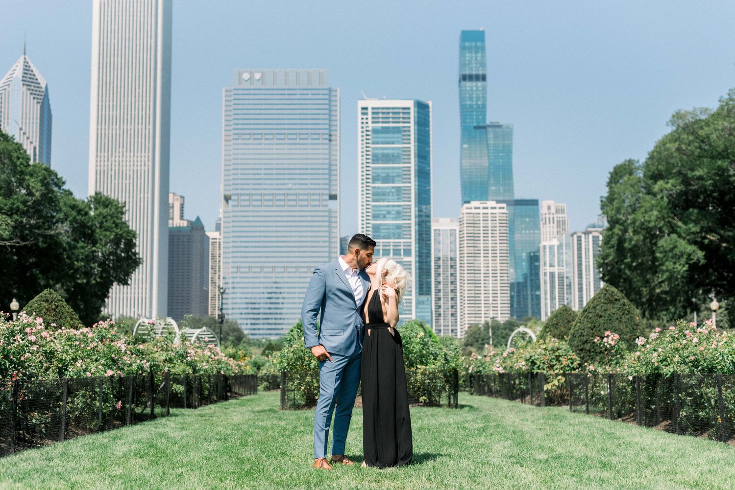 Couple standing in a manicured garden with Chicago's iconic skyline backdrop.