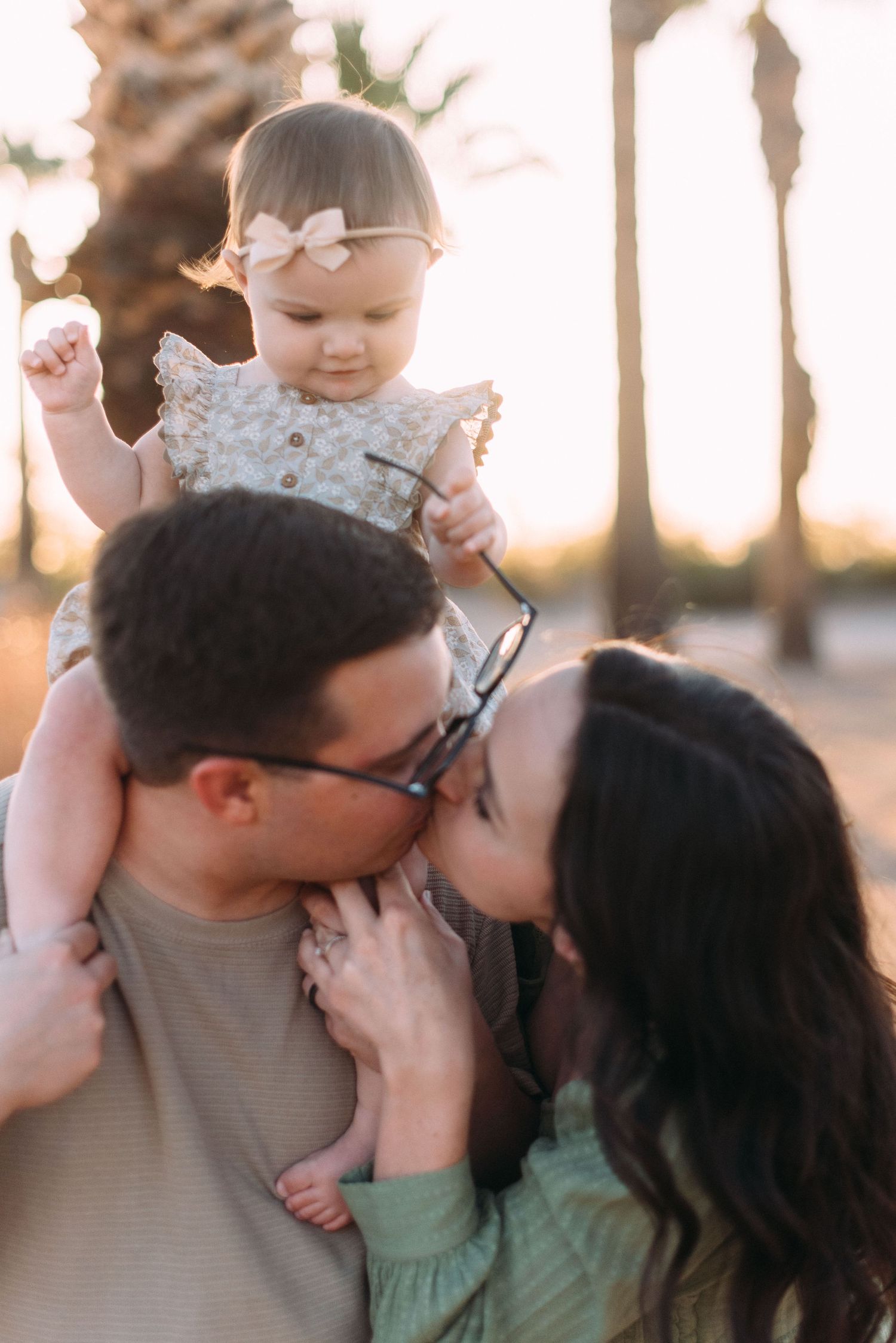 Intimate family portrait during sunset with palm trees silhouetted in background.