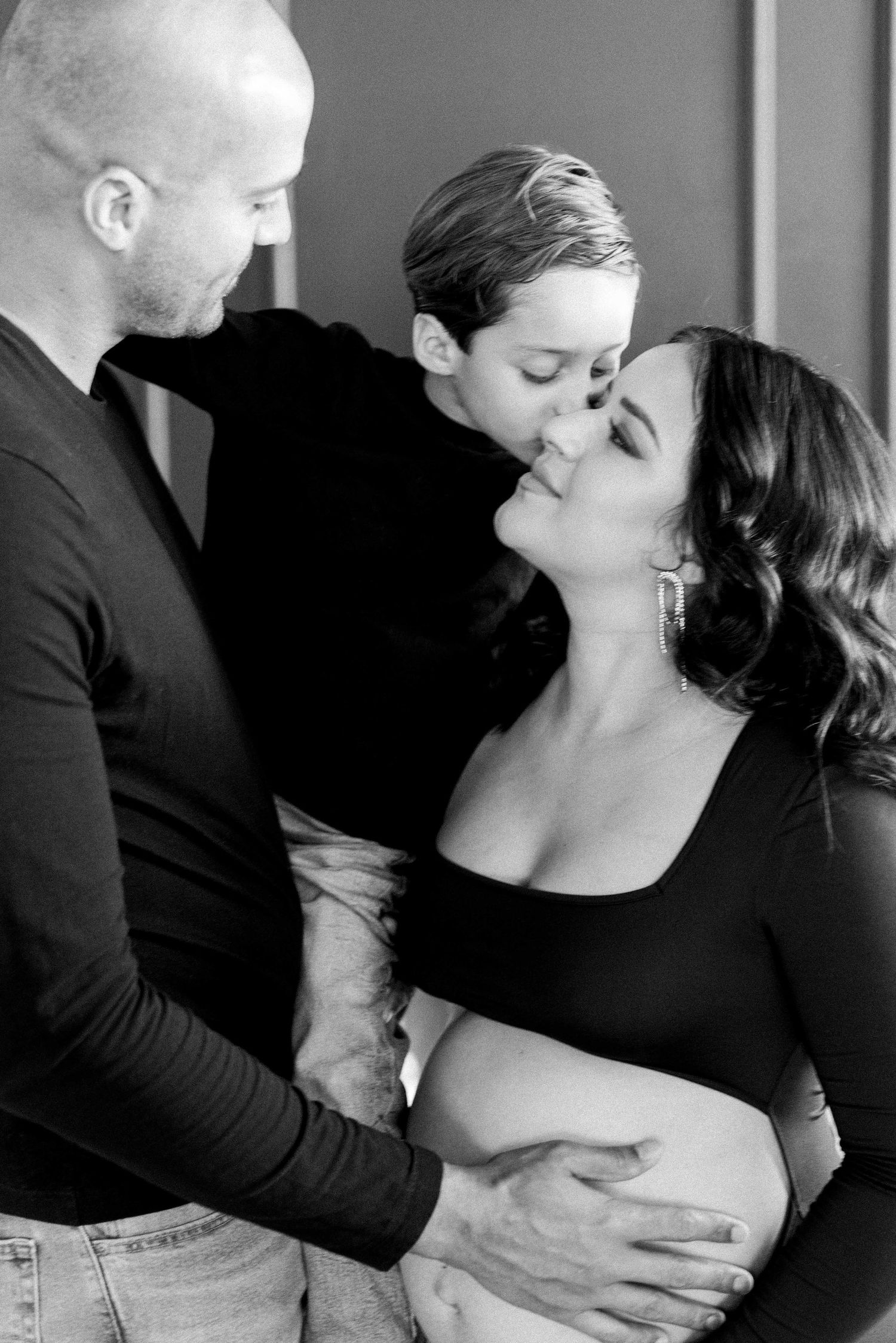 Black and white intimate family maternity photo showing tender moment.