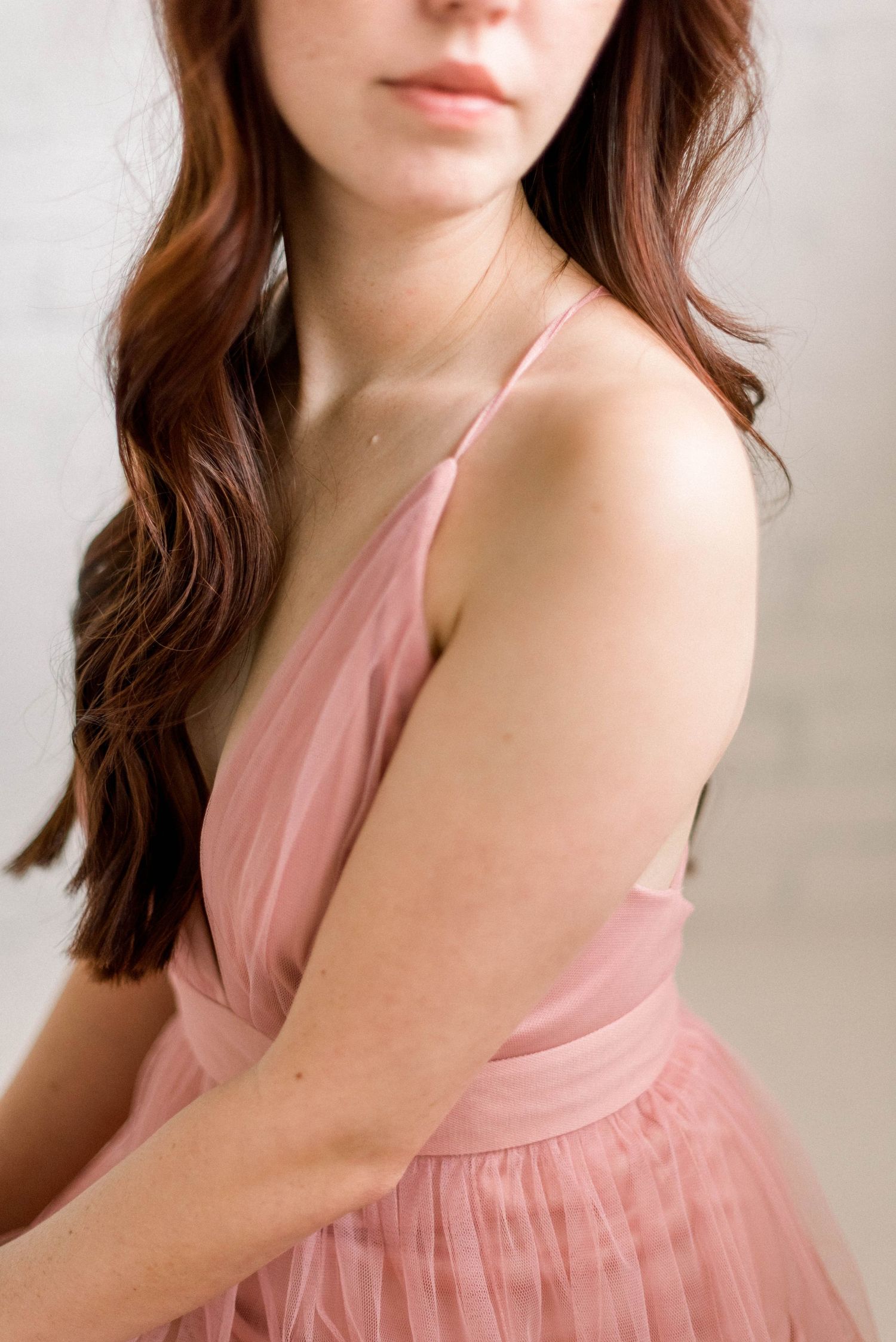 Romantic pink tulle dress with spaghetti straps shown in soft natural light.