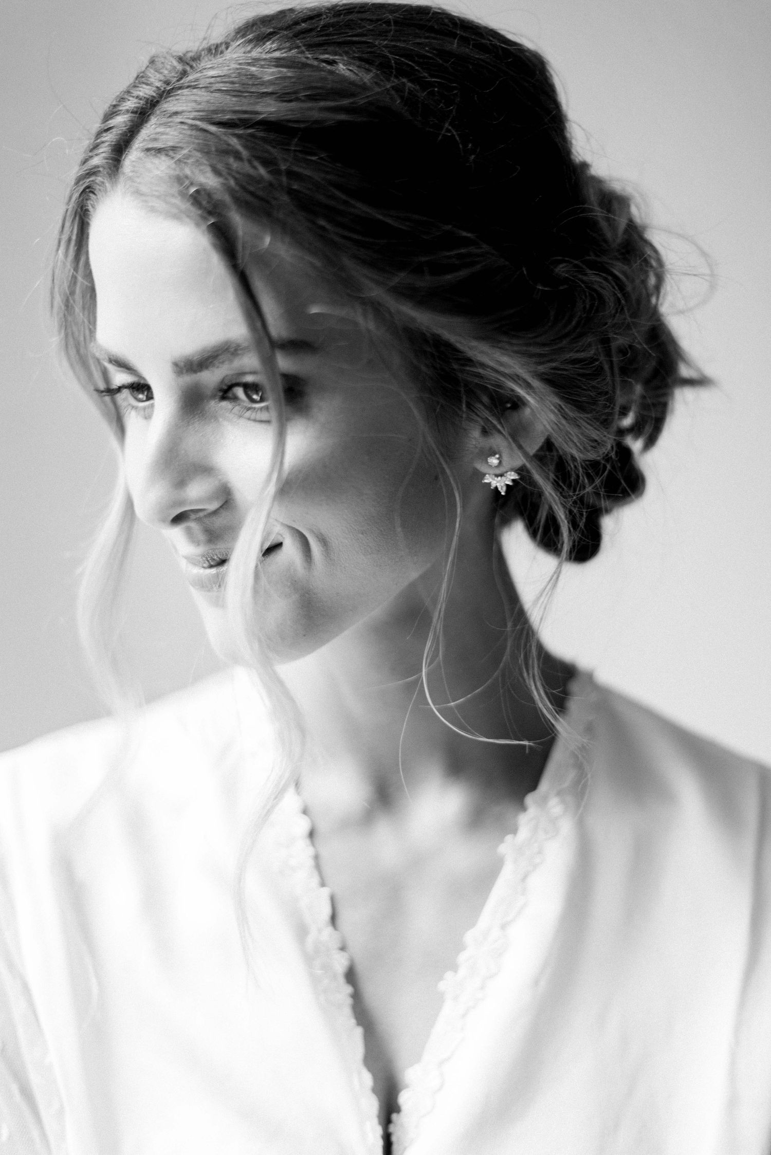 Black and white portrait showing elegant updo hairstyle and earring detail.