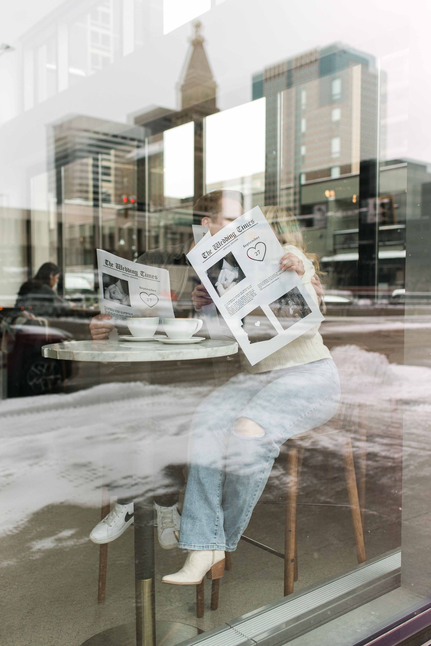 Artistic double exposure photo of a person reading newspaper at a cafe window with city reflections.
