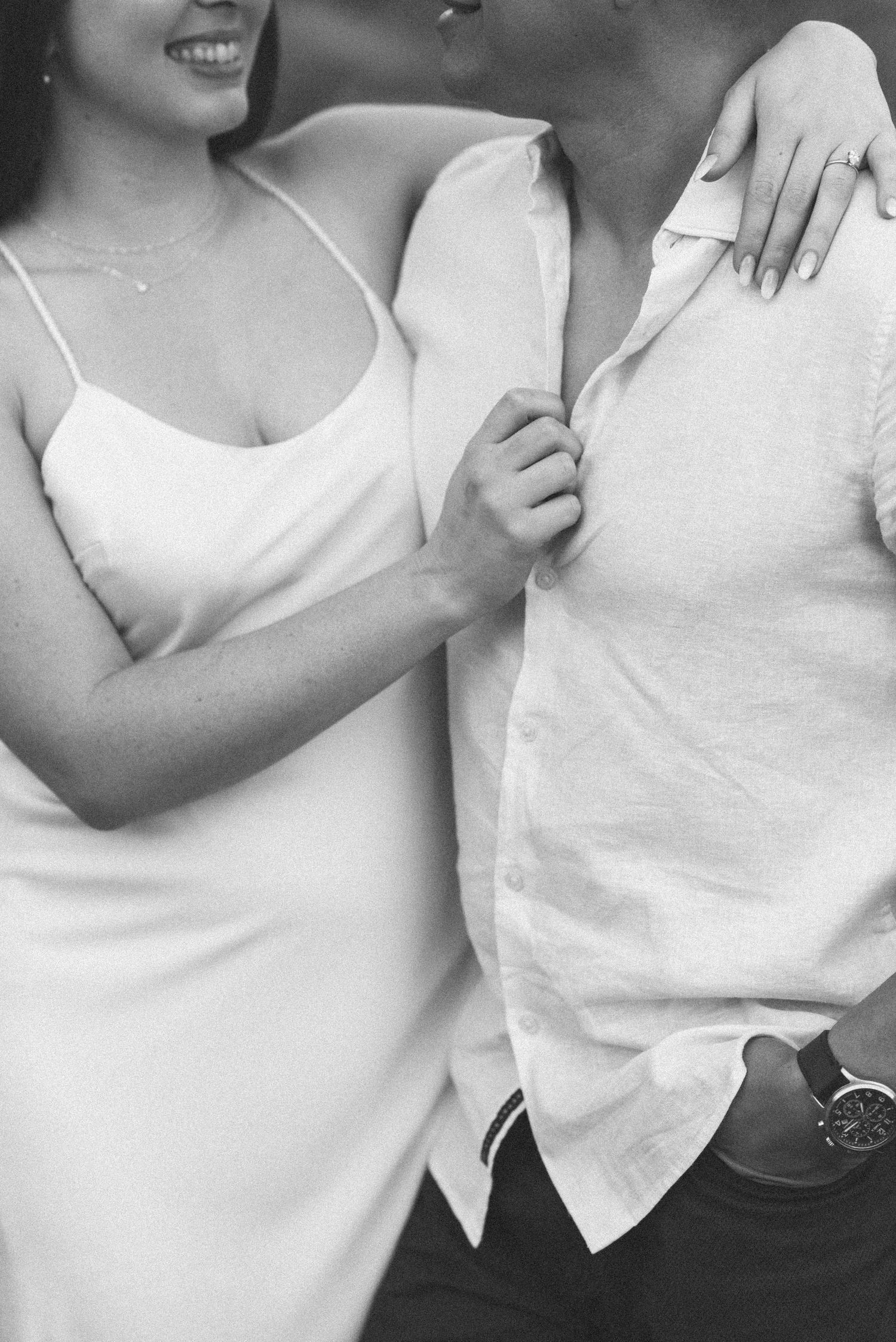 Black and white close-up of a couple in white clothing showing intimate connection.