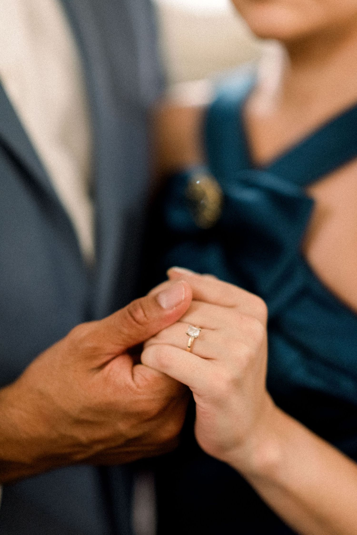Close-up of hands showing an engagement ring in an intimate moment between a couple.