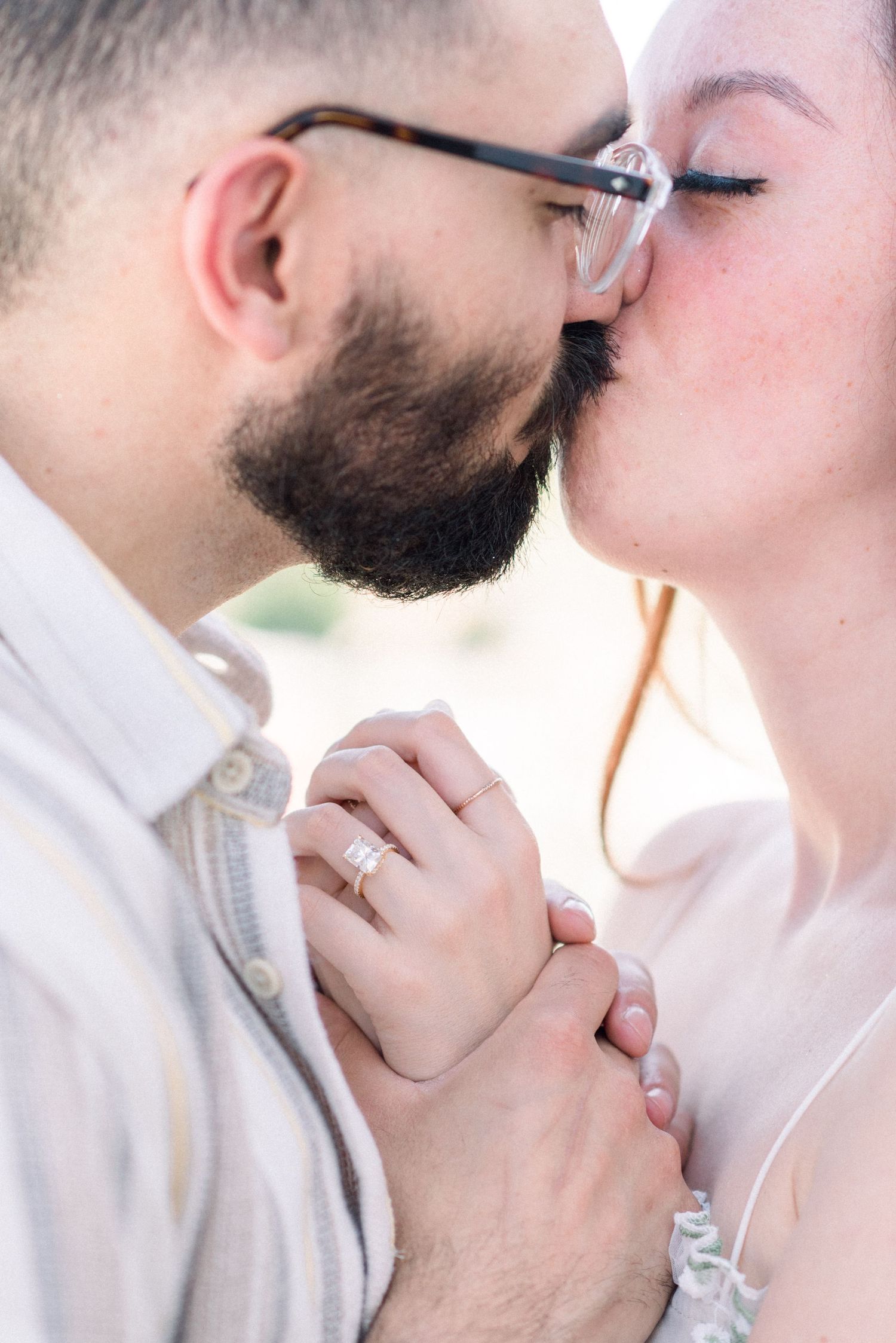 Close up of an intimate moment between a couple showing clasped hands and engagement ring.