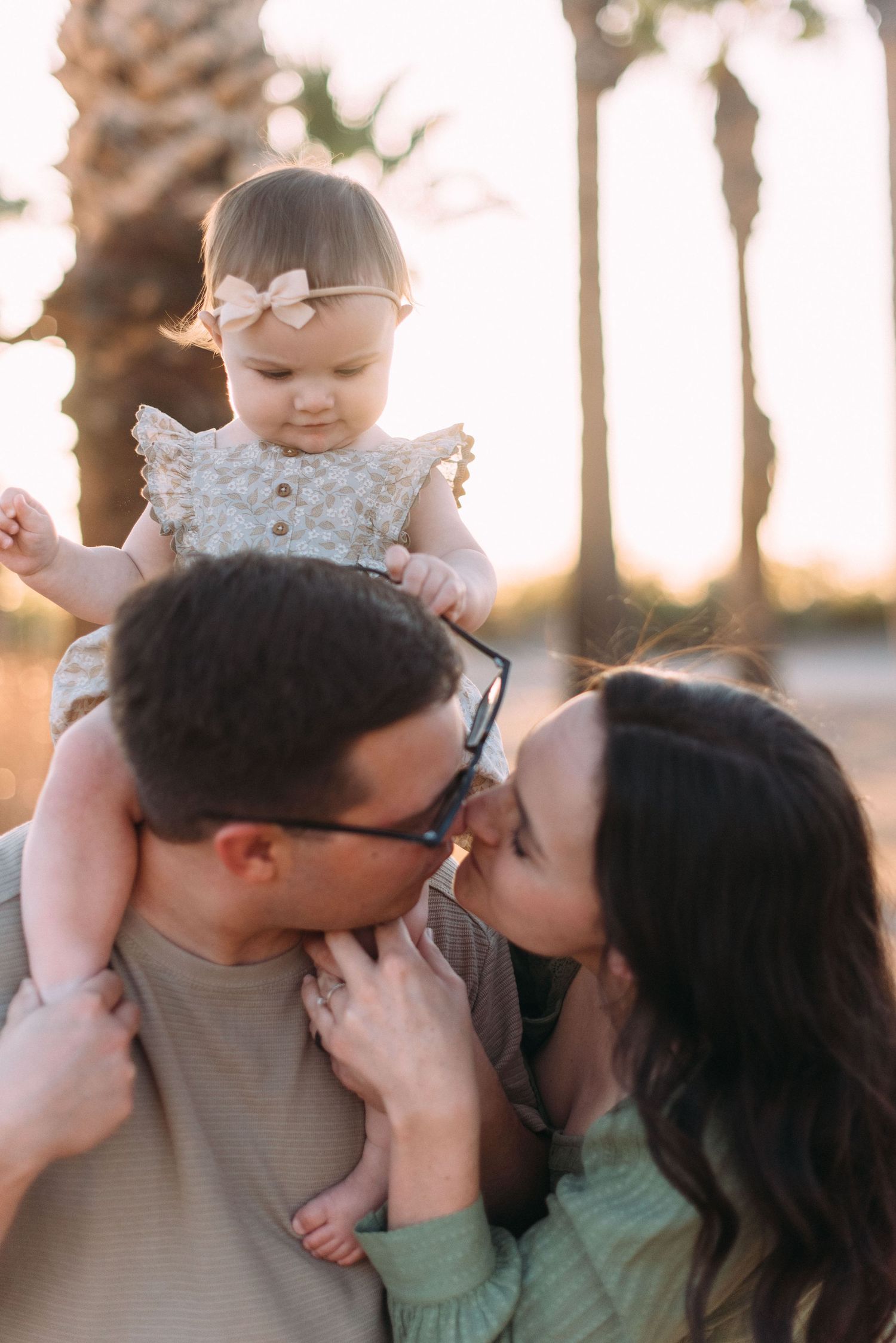 Sweet family portrait with baby on shoulders during golden hour photoshoot.