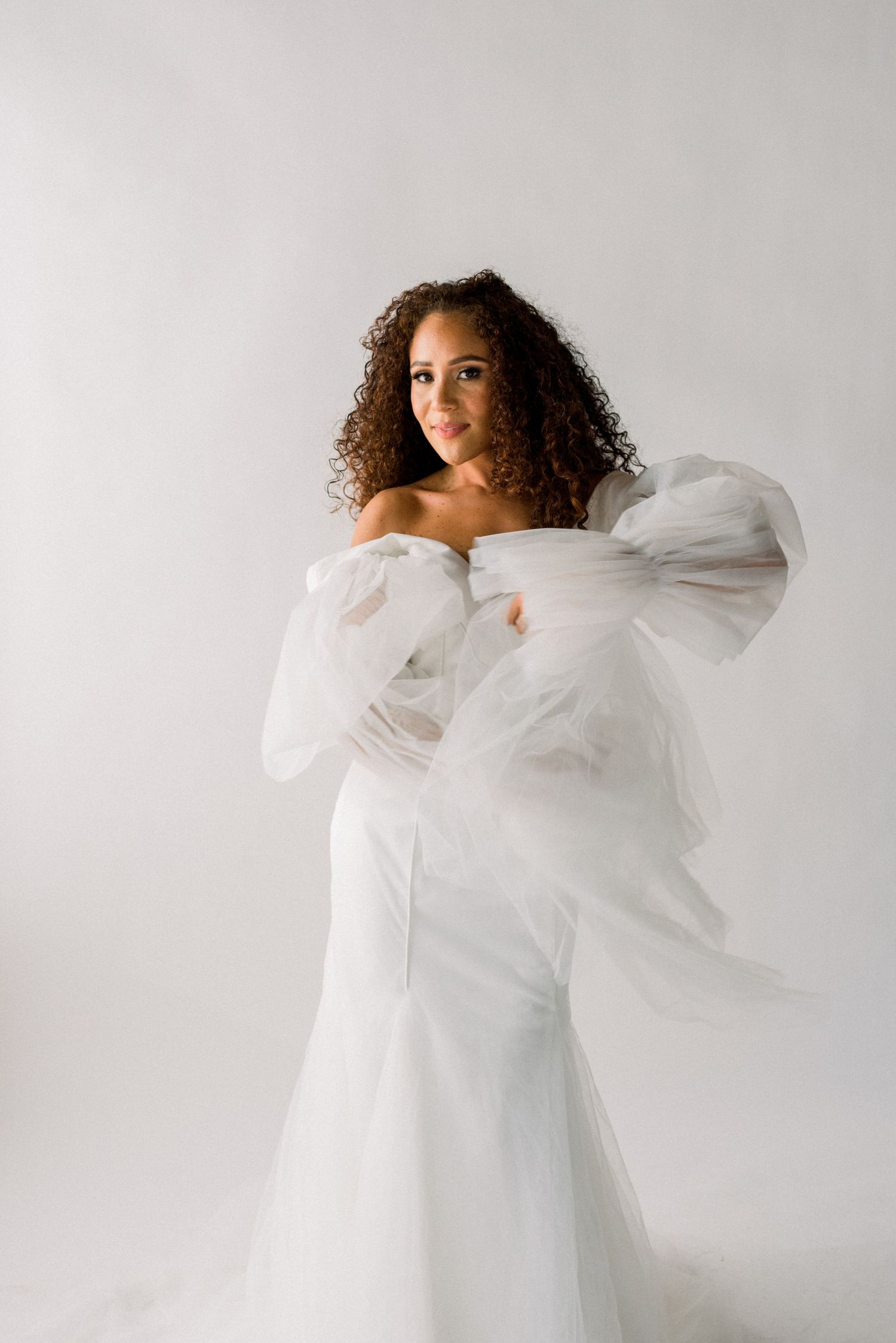Elegant bride in form-fitting white gown with dramatic puffy sleeves.