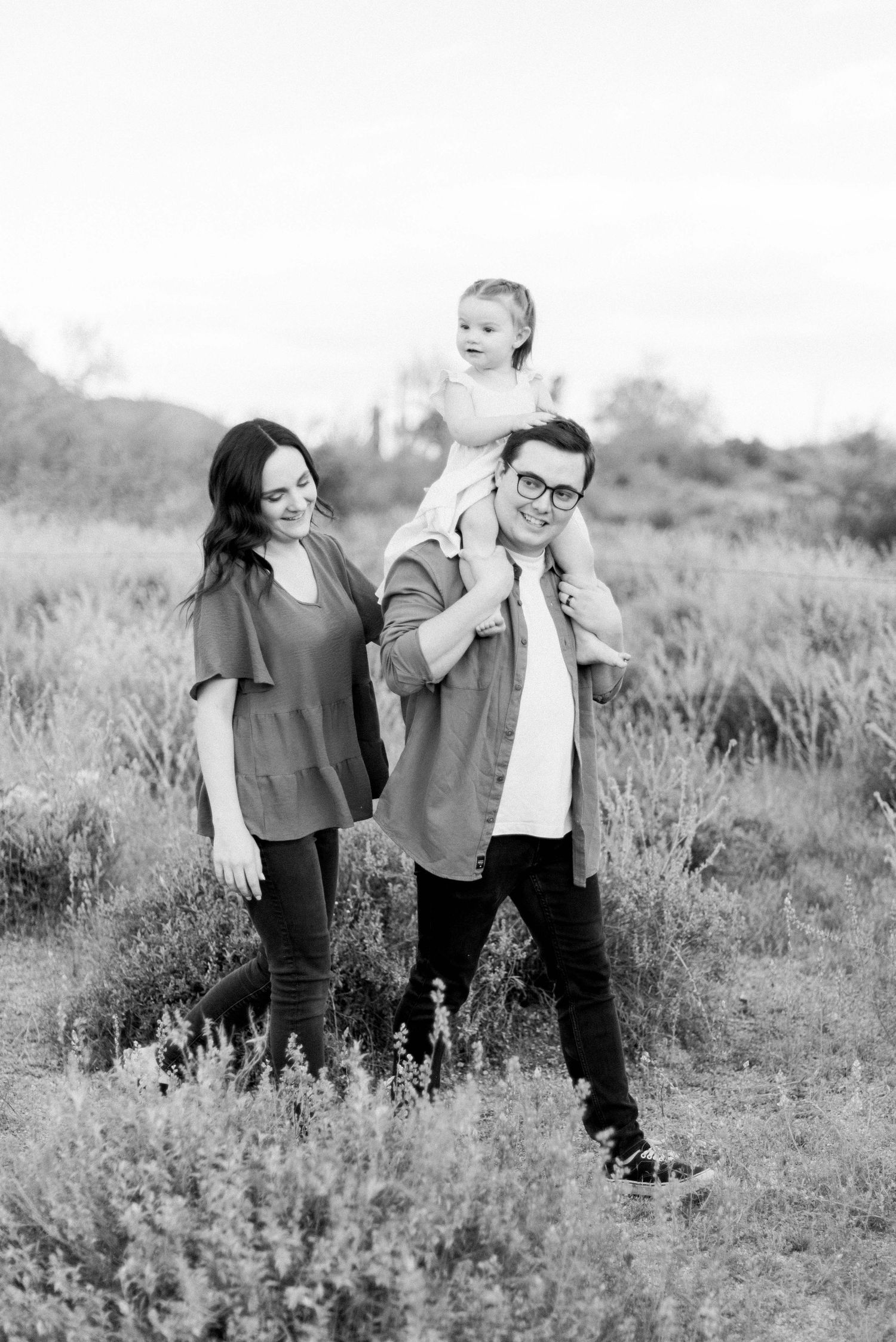 Black and white family portrait in desert landscape with mountains.