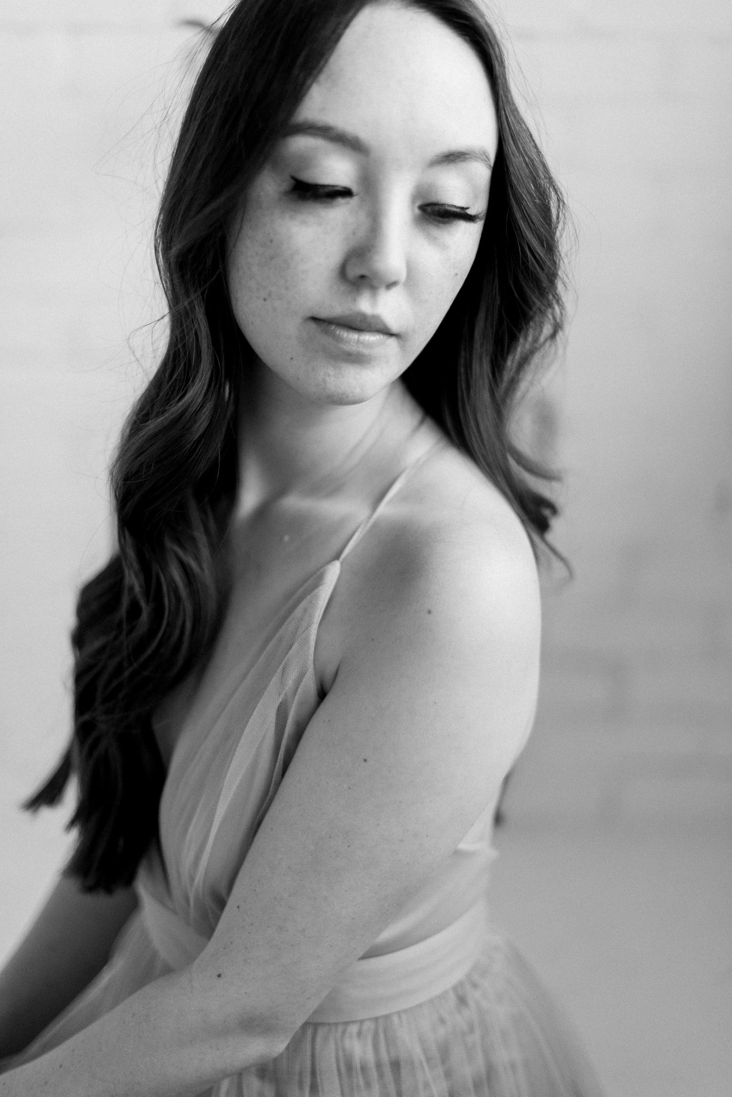 Black and white portrait with soft lighting and delicate dress details.