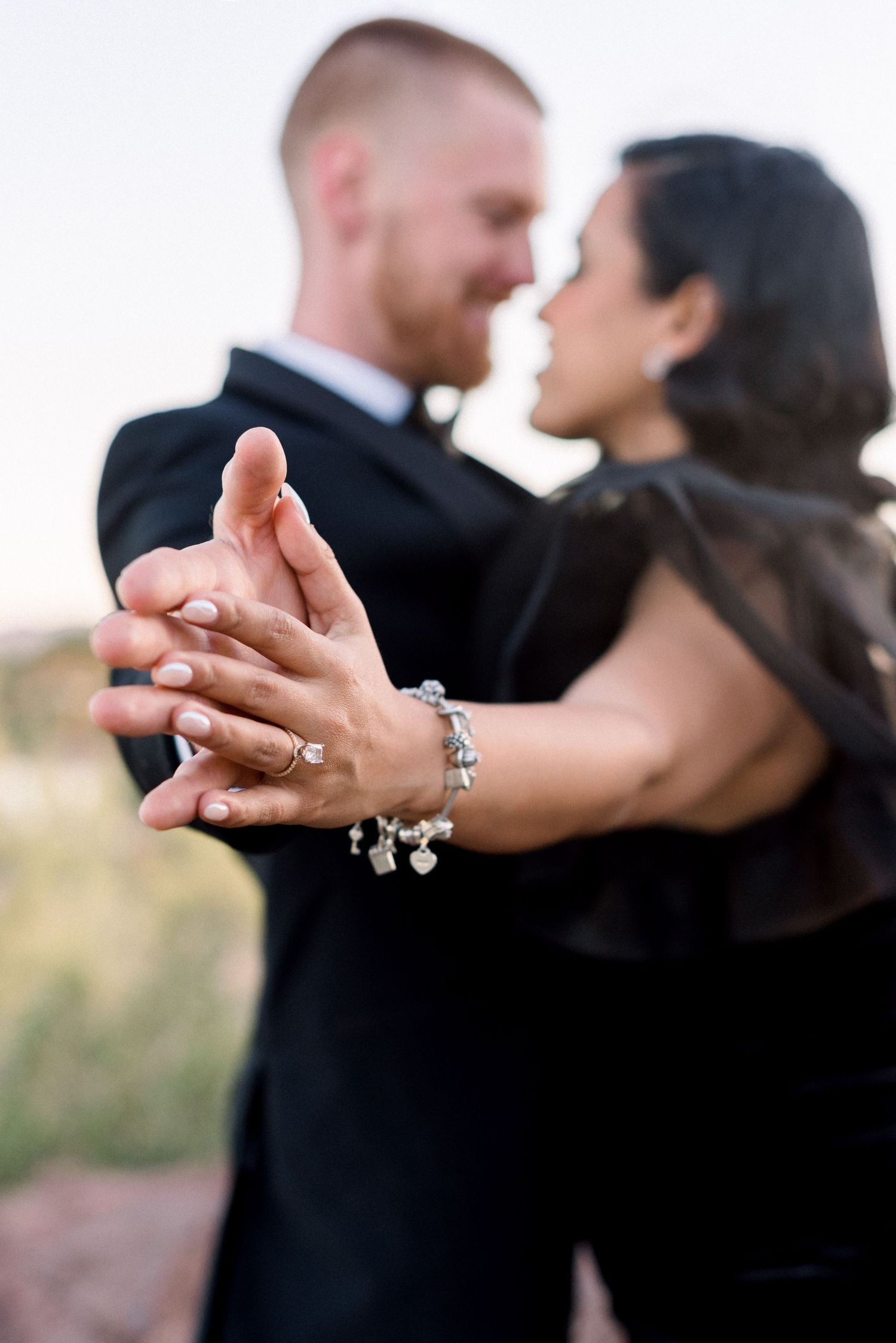 Close-up of dancing couple's hands with jewelry during their formal photo session.
